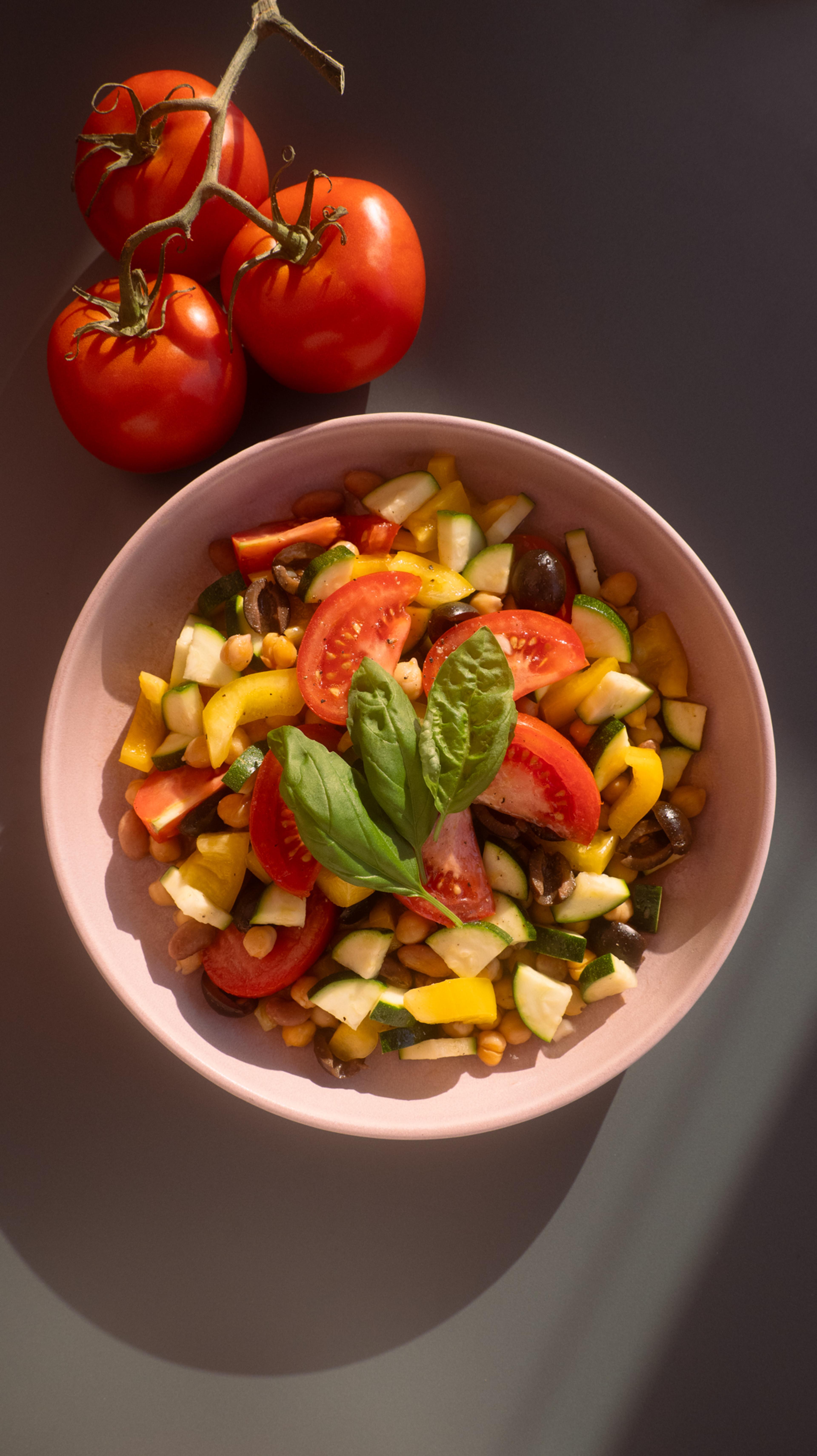 Chickpea Tomato Puttanesca Salad plated near a heirloom tomato from a Los Angeles Farmers Market