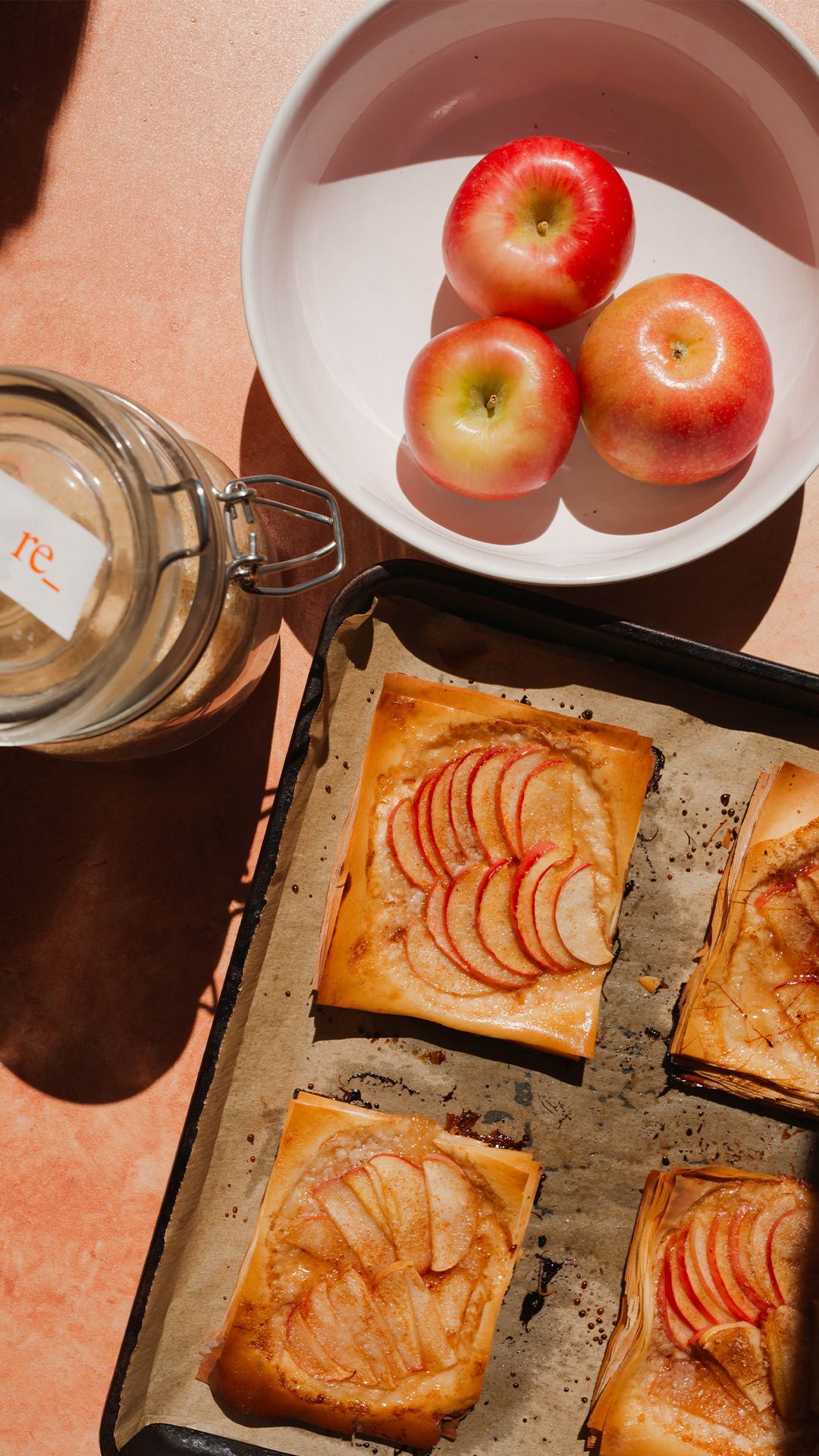 fall apples in a bowl next to a plate of apple tarts
