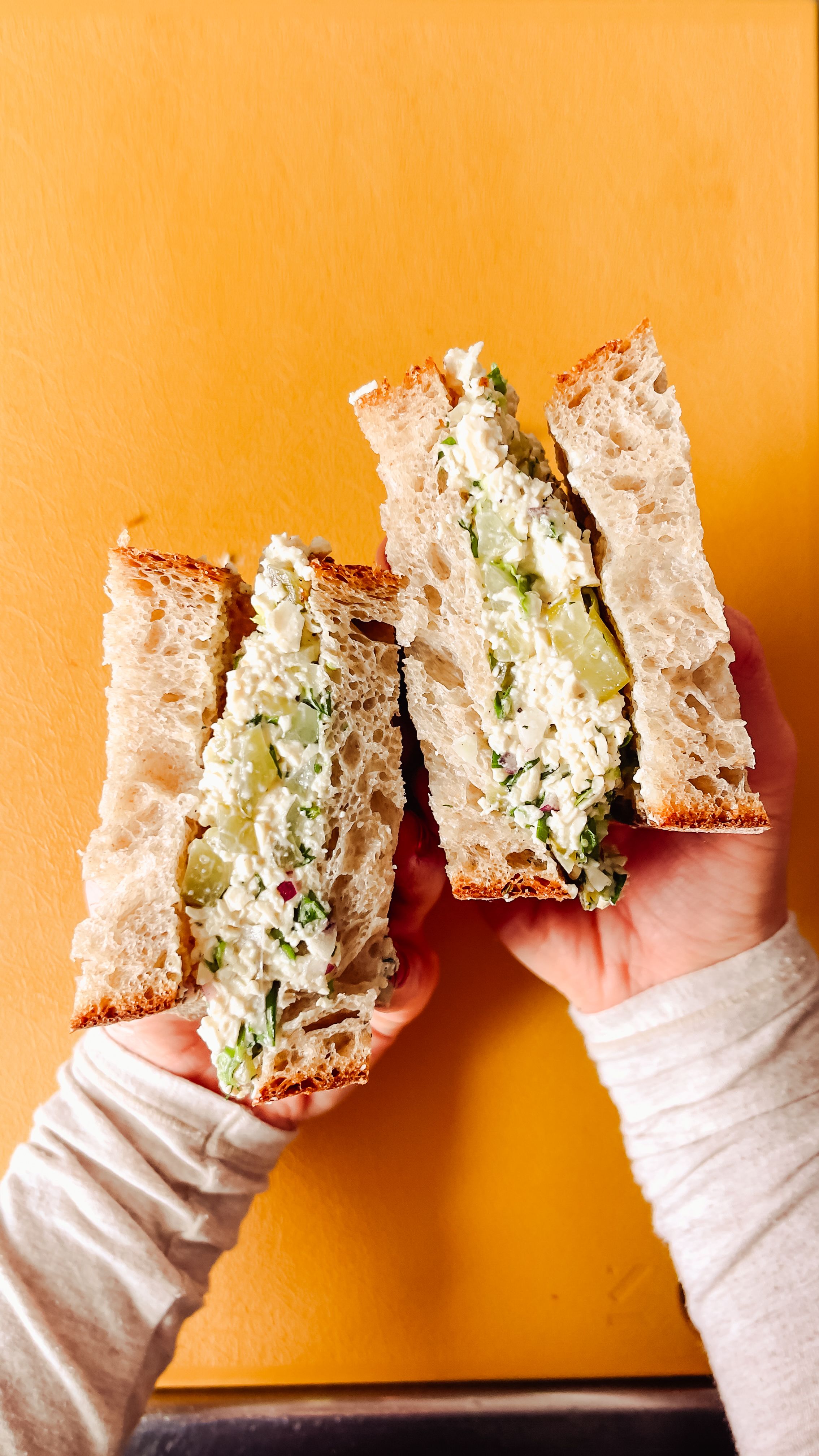 tofu salad sandich cut in half on an orange background