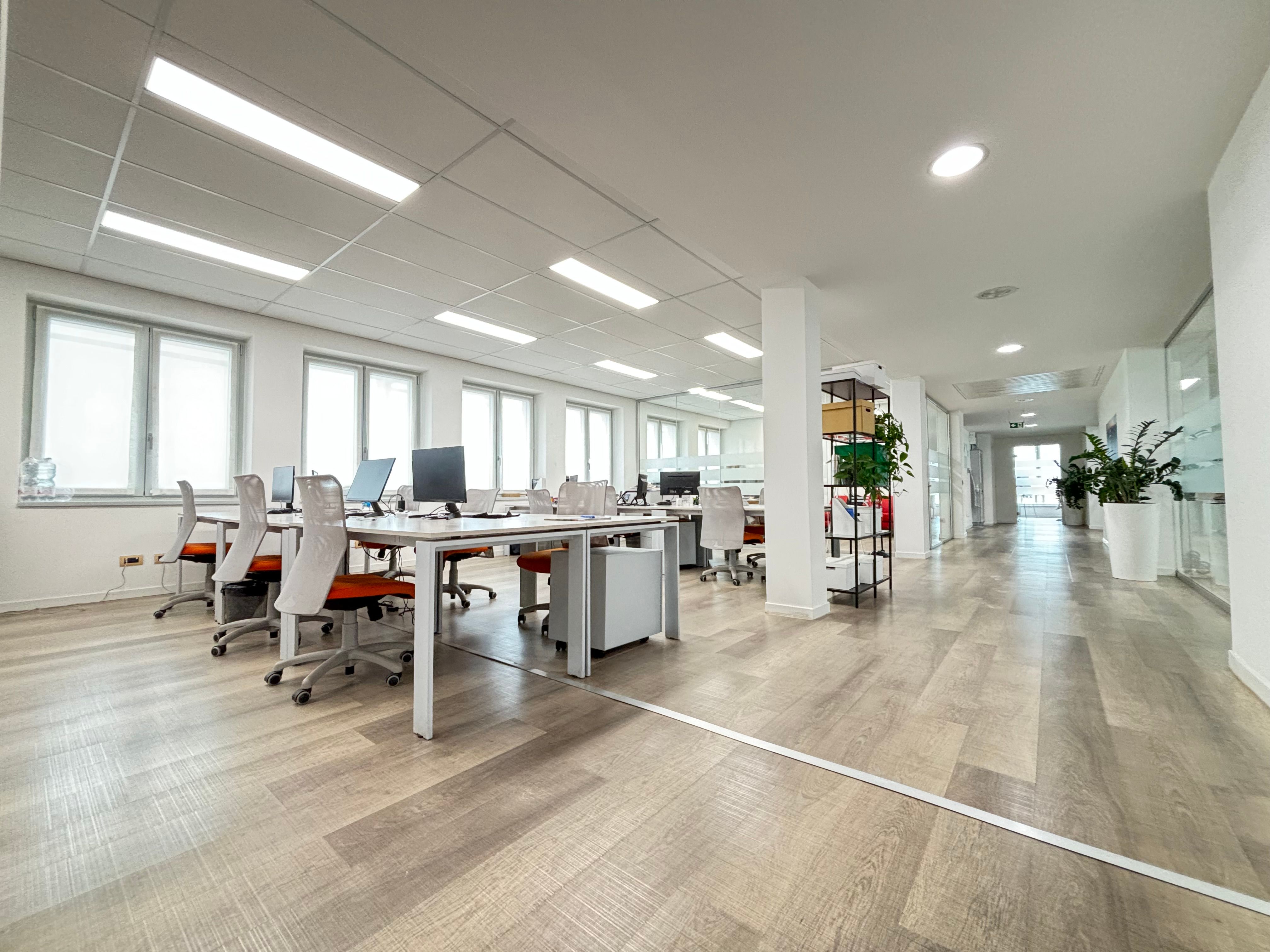 interno ufficio, open sapece, con tavoli e sedie, computer e telefoni, finestre