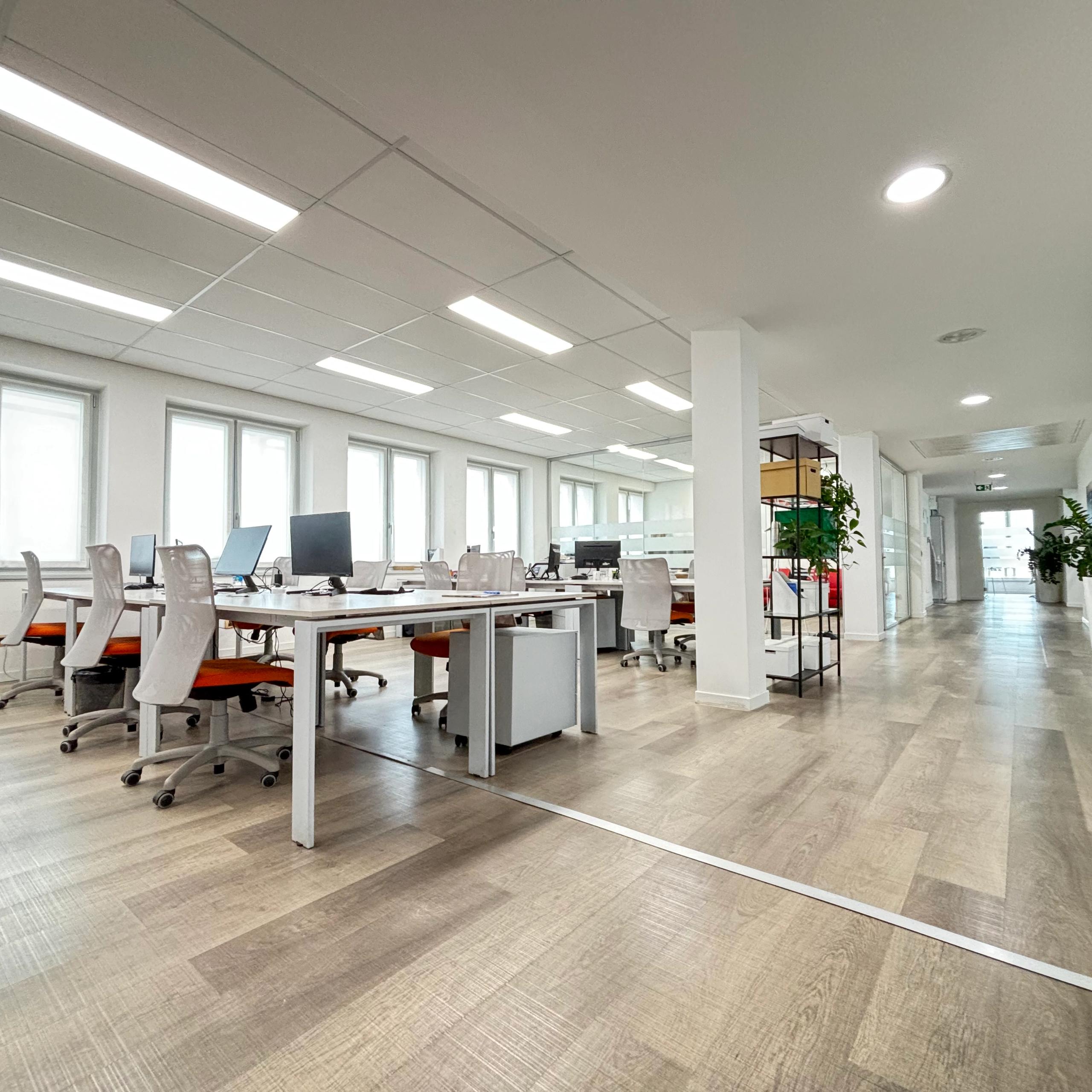 interno ufficio, open sapece, con tavoli e sedie, computer e telefoni, finestre