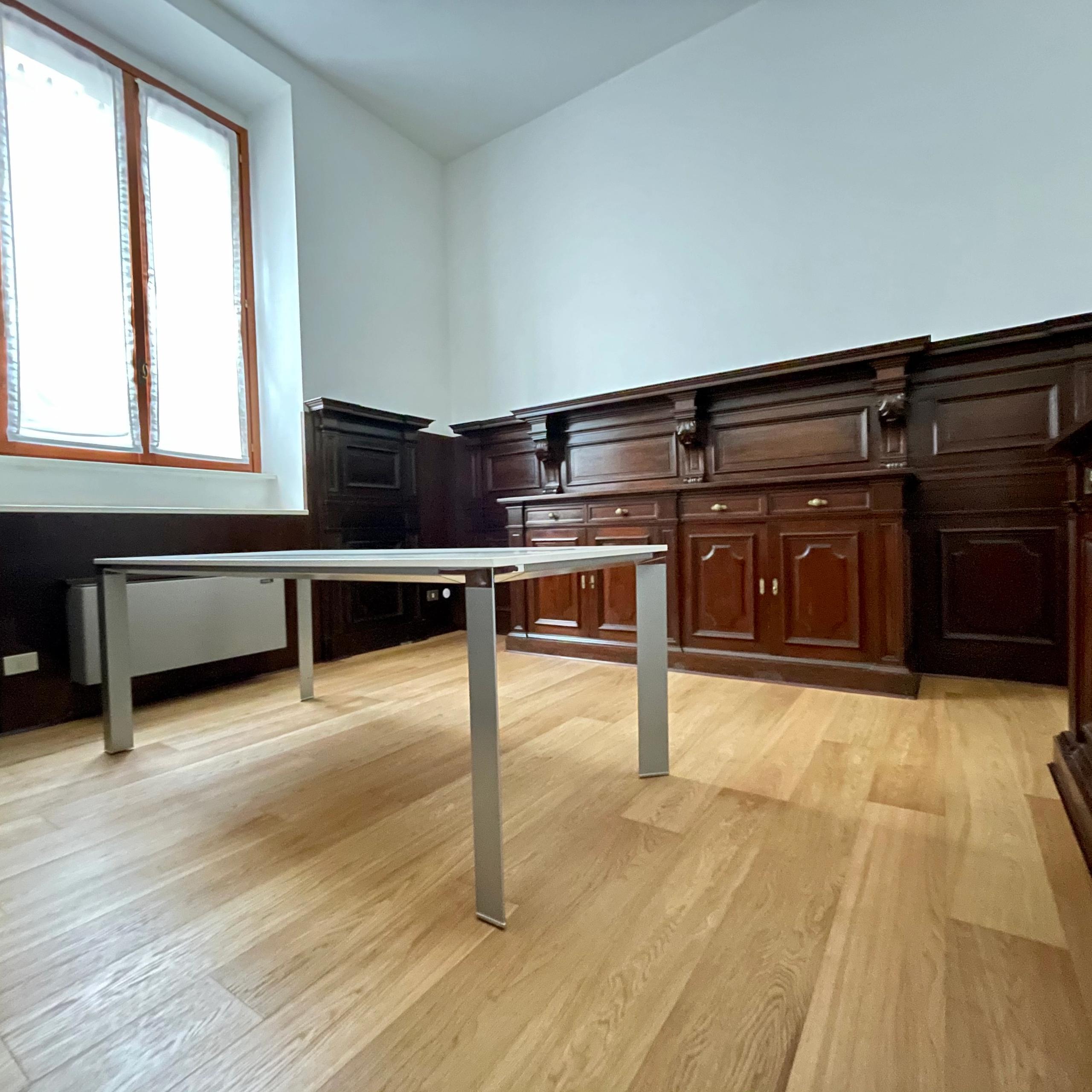 Uffico con parquet, pareti in legno scuro, finestra con tende, tavolo