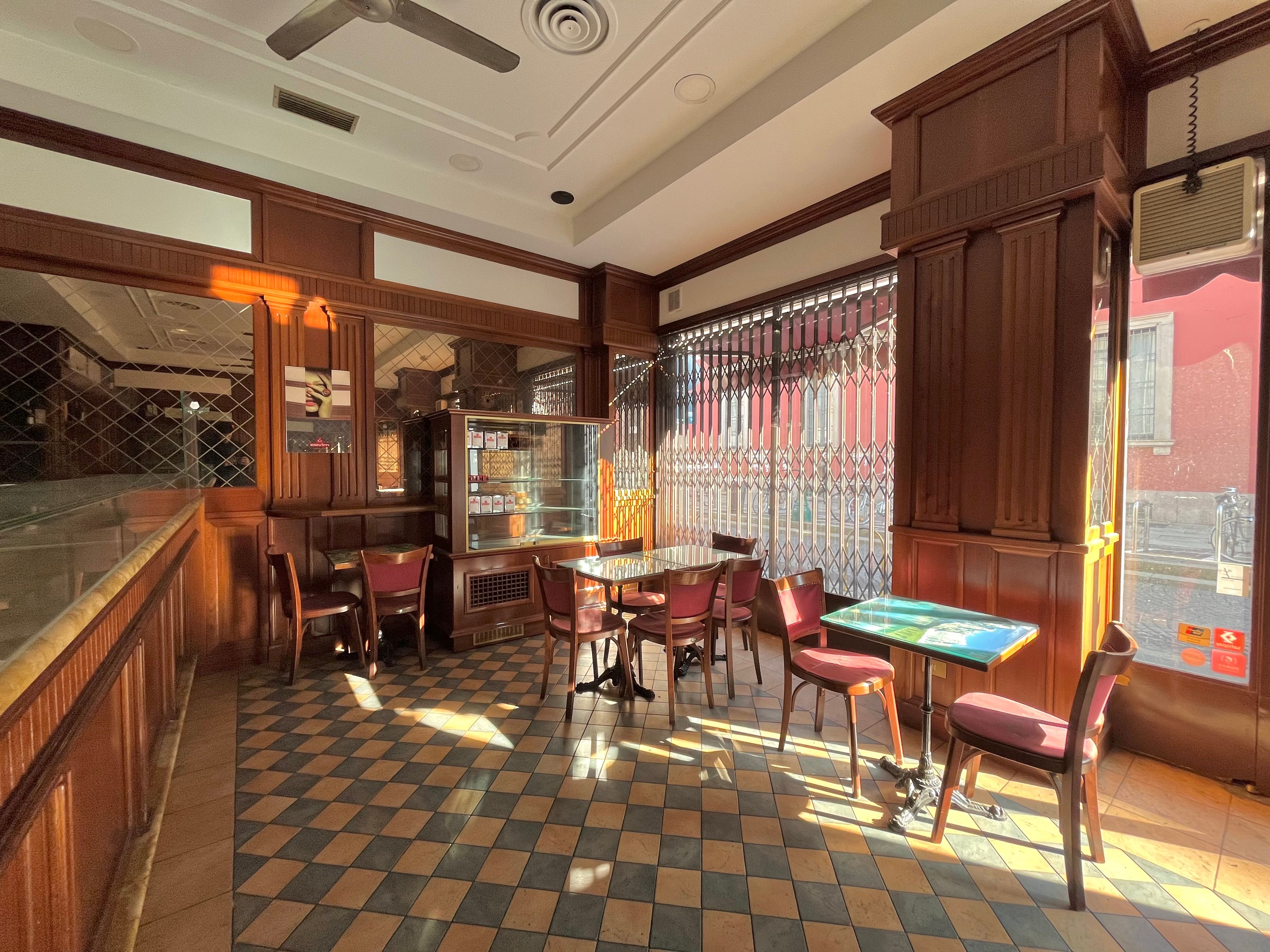 Bar interior, with counter, storefront window, small tables and chairs, wall mirrors, ceiling fans