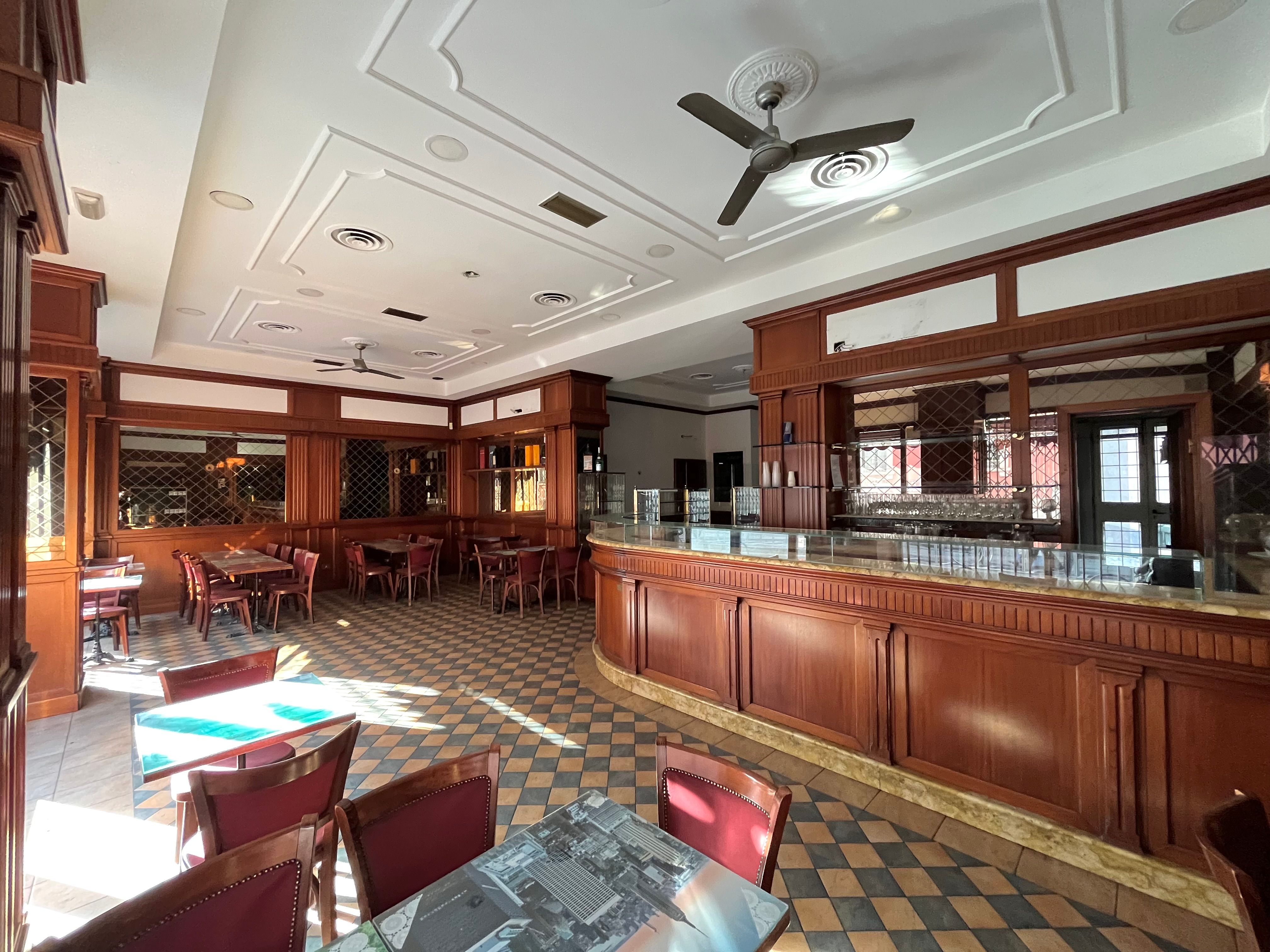 Bar interior, with counter, storefront window, small tables and chairs, wall mirrors, ceiling fans