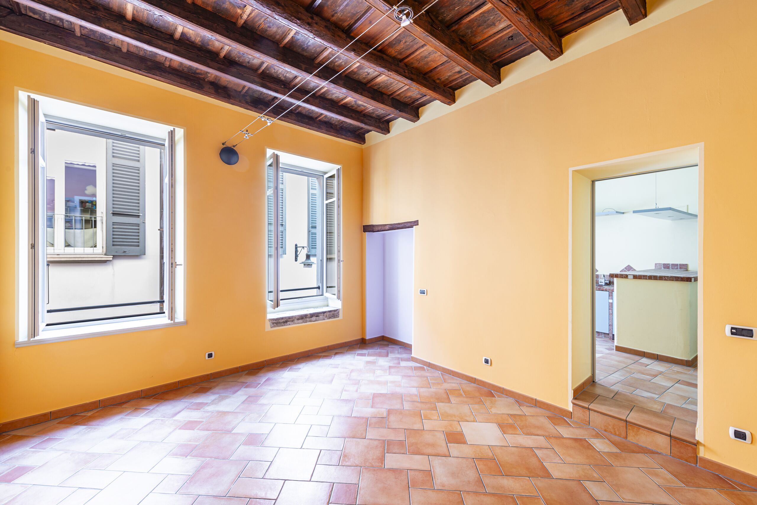 living room with windows, door facing the kitchen, wooden ceiling