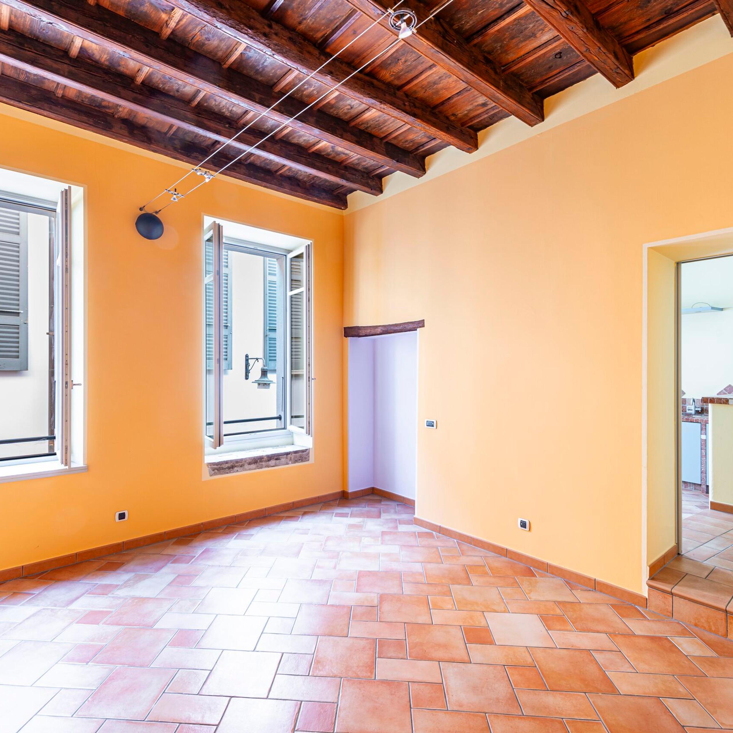 living room with windows, door facing the kitchen, wooden ceiling