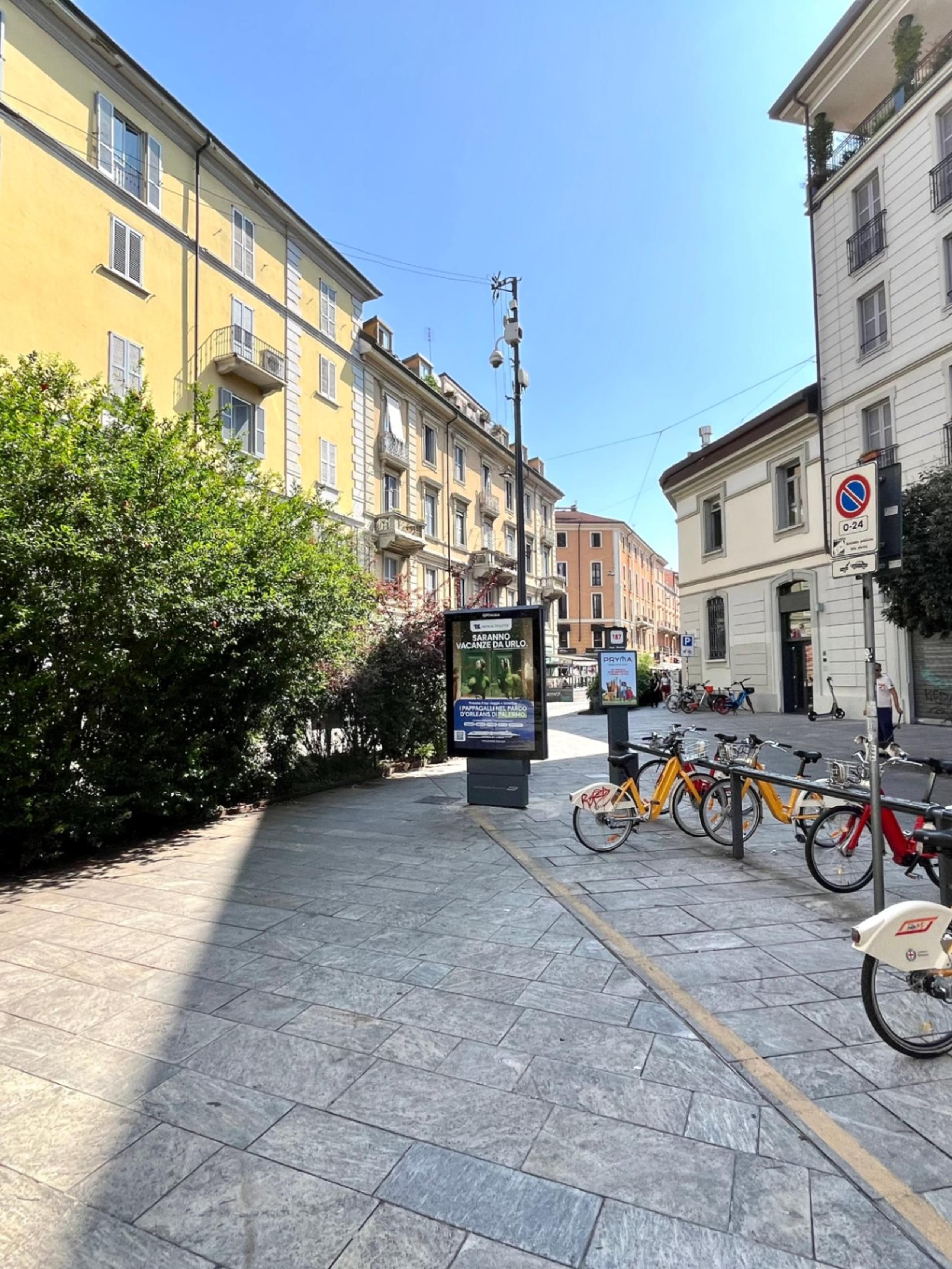 piazza, bicing, piante, palazzi con finestre e balconi, negozi