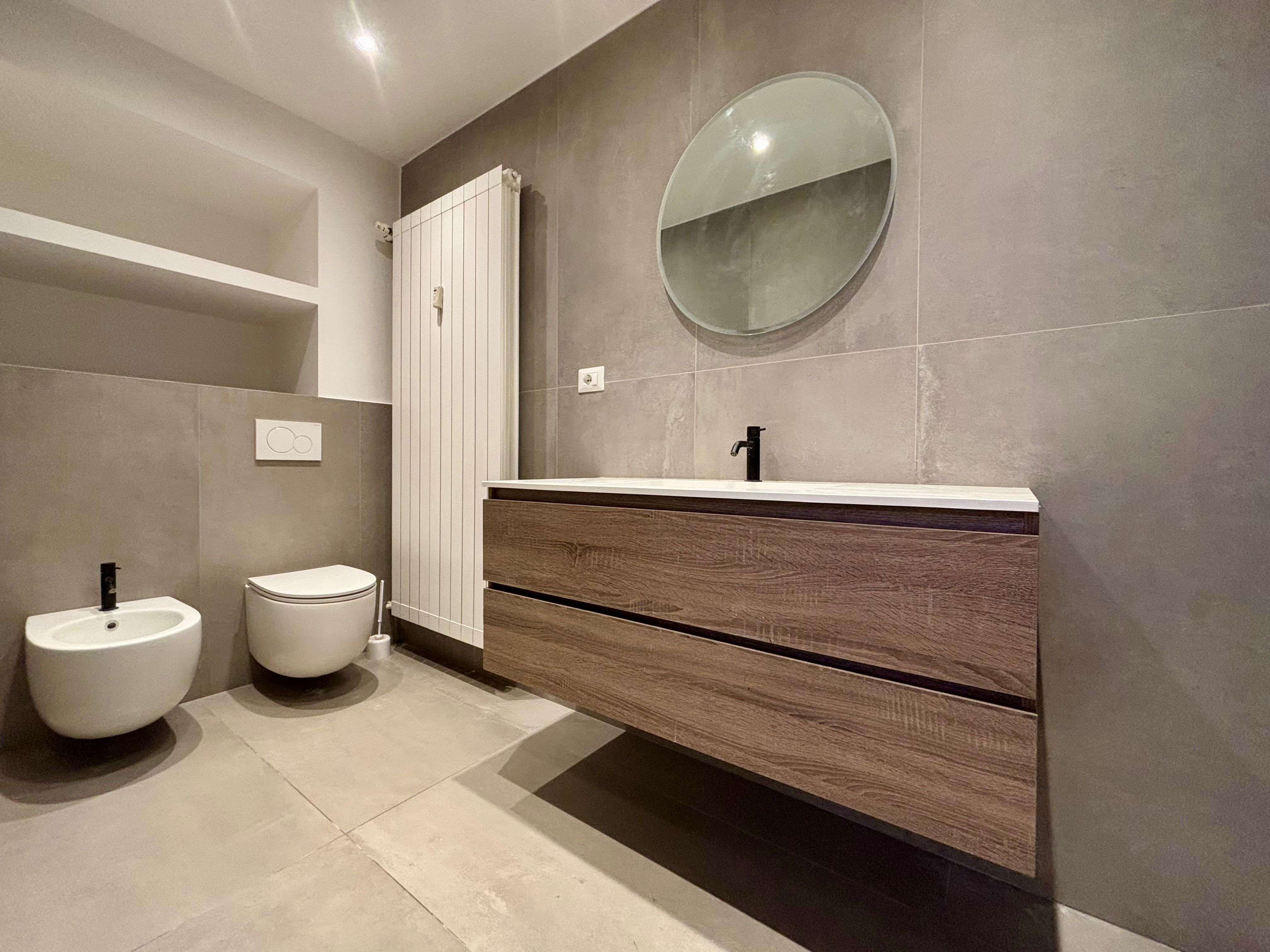 bathroom with sink and mirror, toilets and heater
