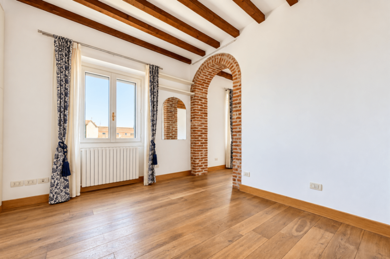 muro bianco, porta ad arco con mattoni a vista, travi a vista