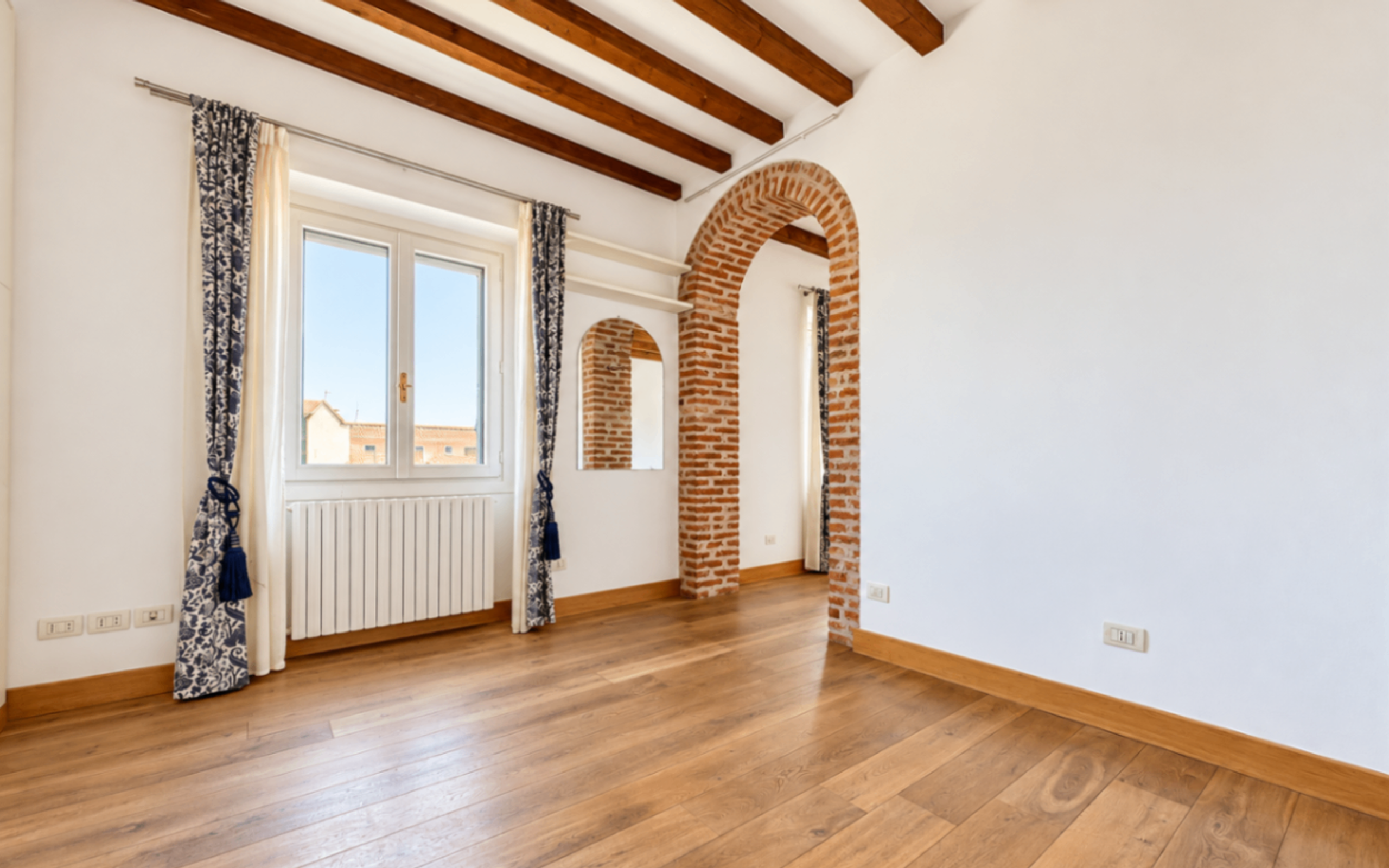 muro bianco, porta ad arco con mattoni a vista, travi a vista