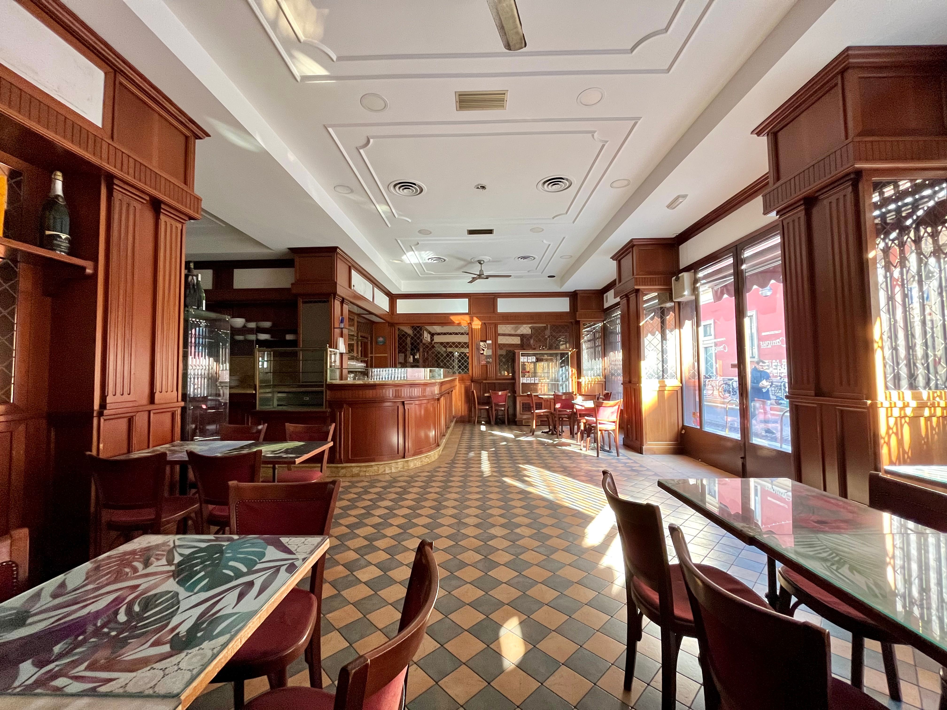 Bar interior, with counter, storefront window, small tables and chairs, wall mirrors, ceiling fans