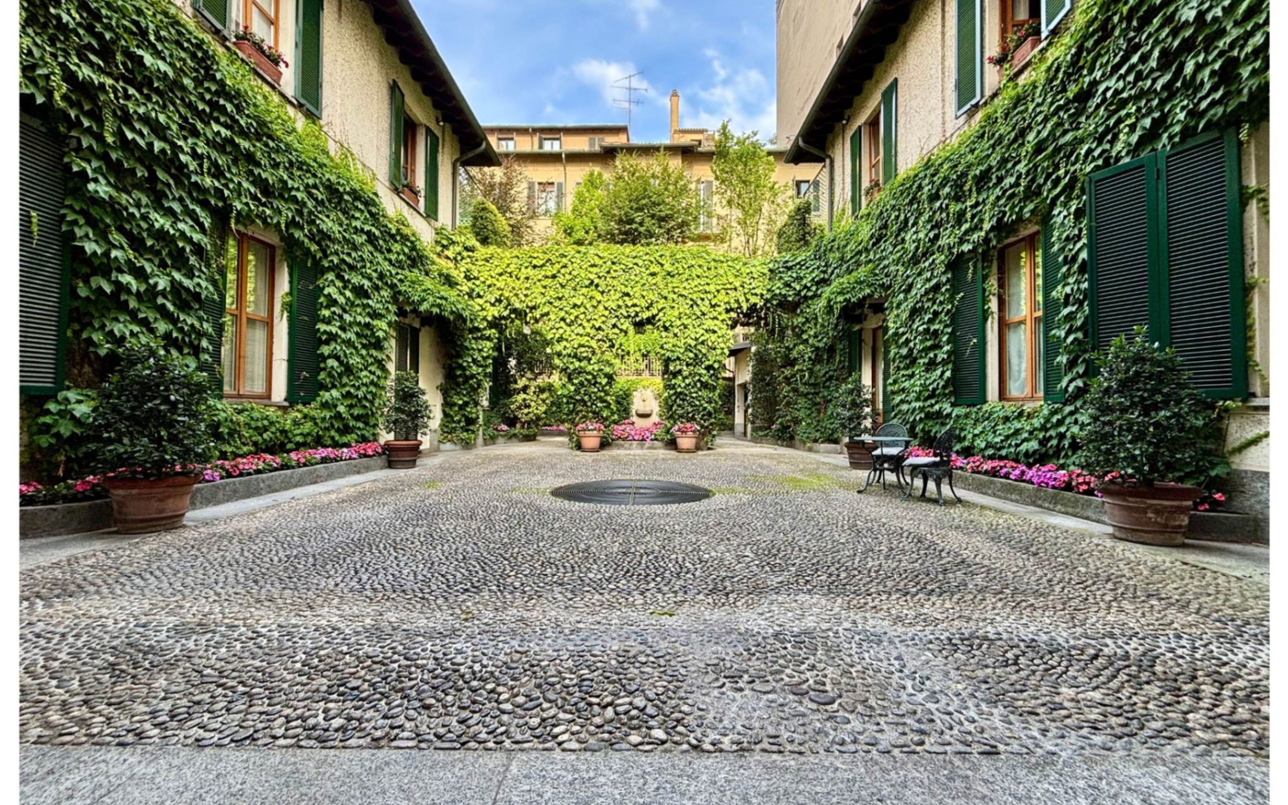 cortile interno, con edera rampicante, finestre e fiori