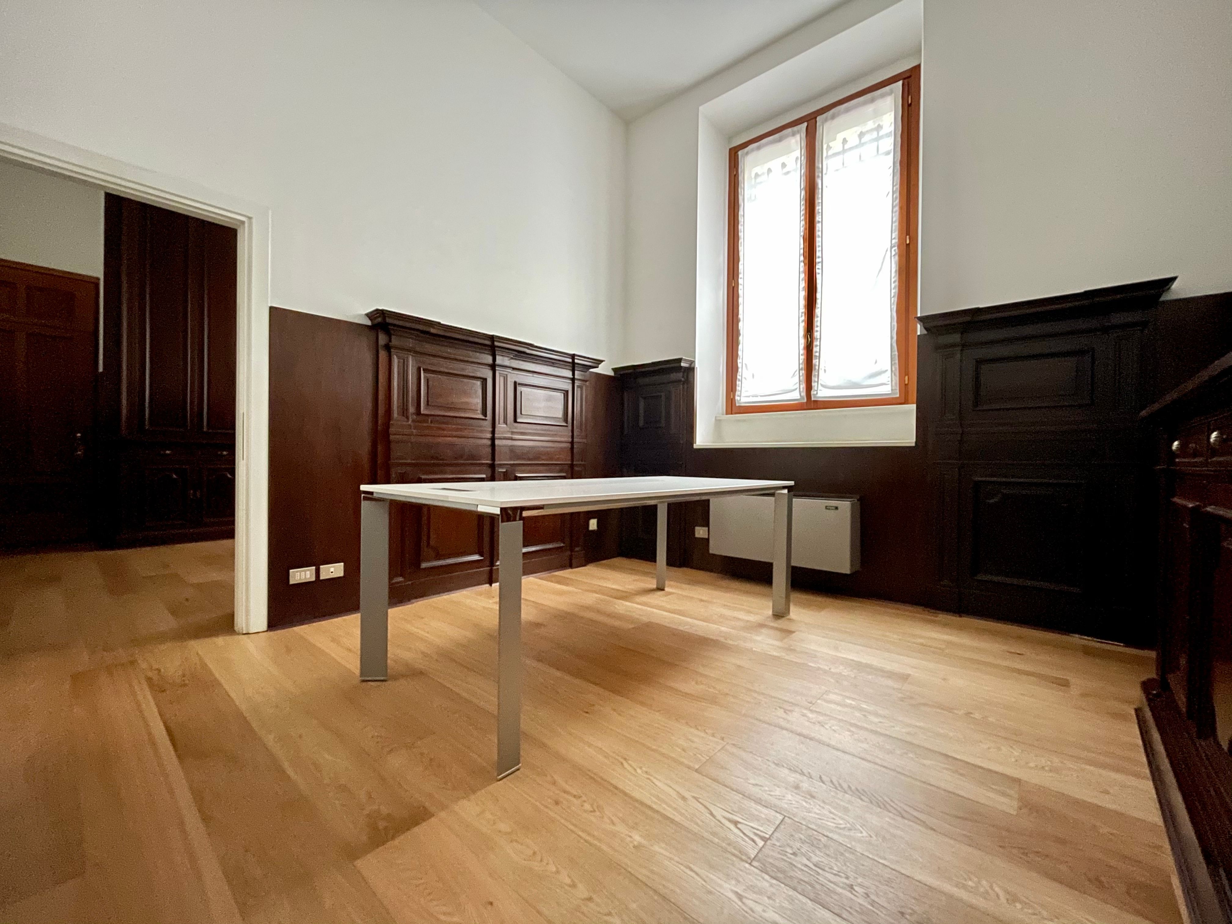 Uffico con parquet, pareti in legno scuro, finestra con tende