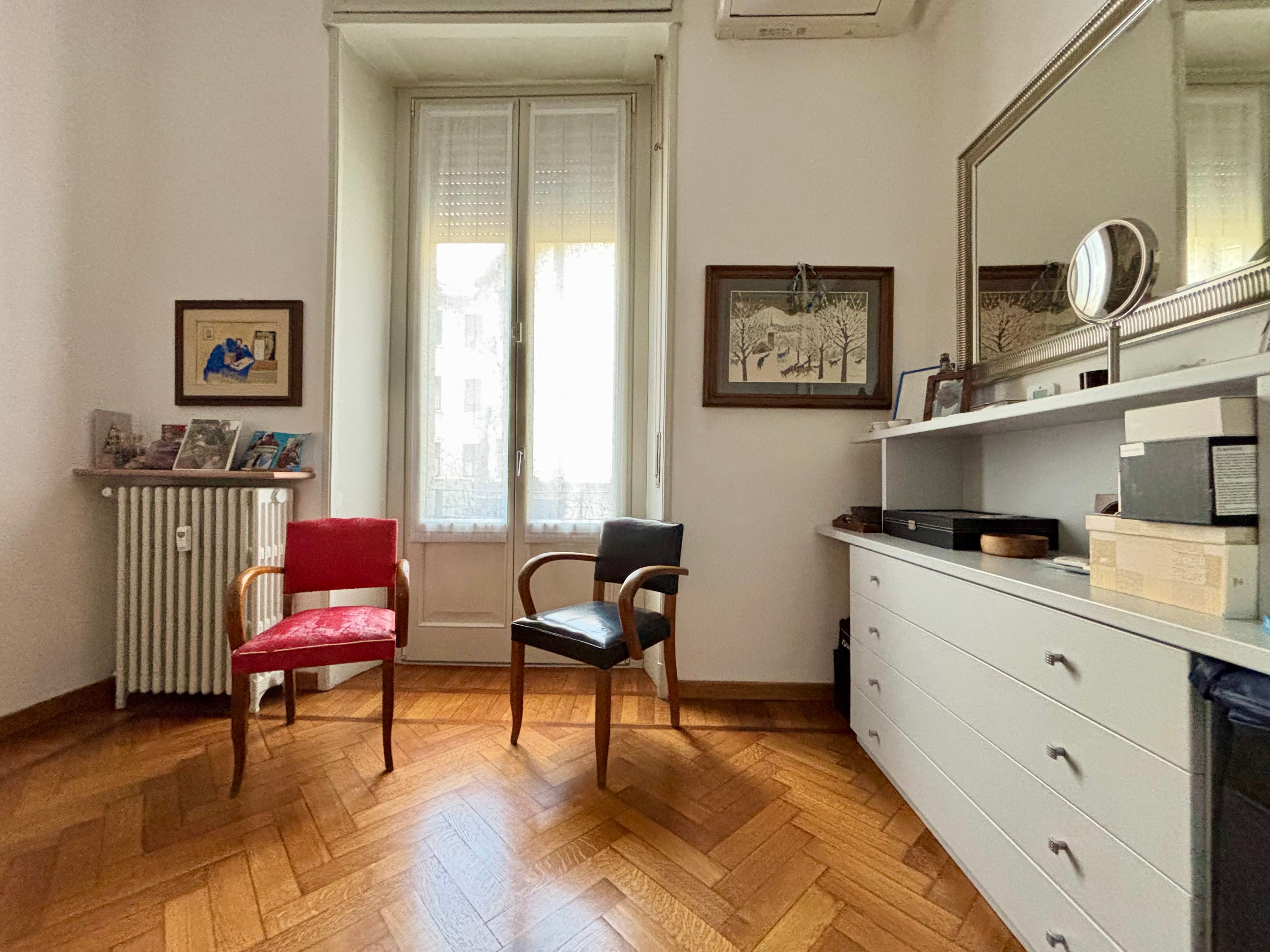 room with window, mirror, two chairs, chest of drawers, heaters