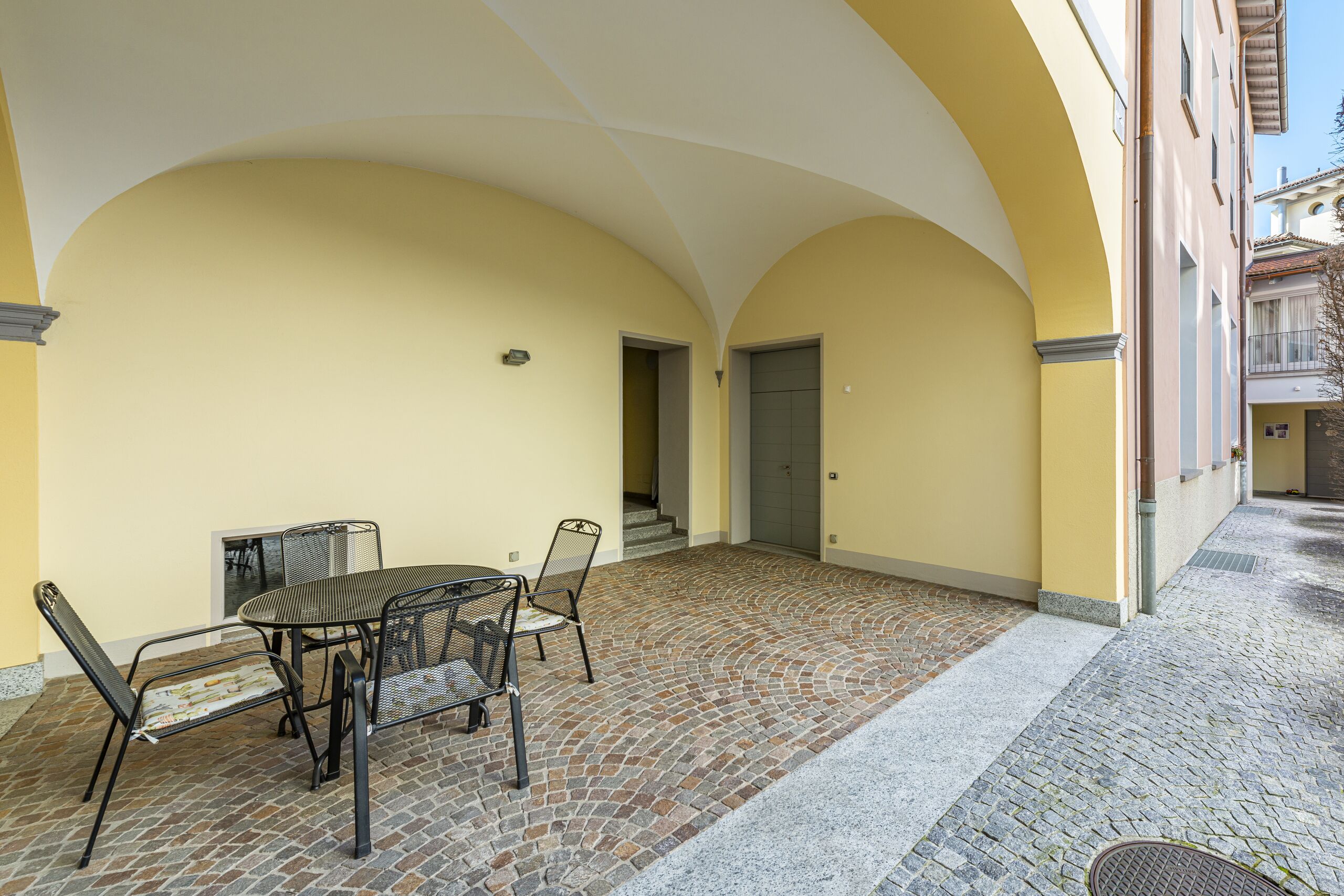 inner backyard, table with chairs, arch, windows, residential building