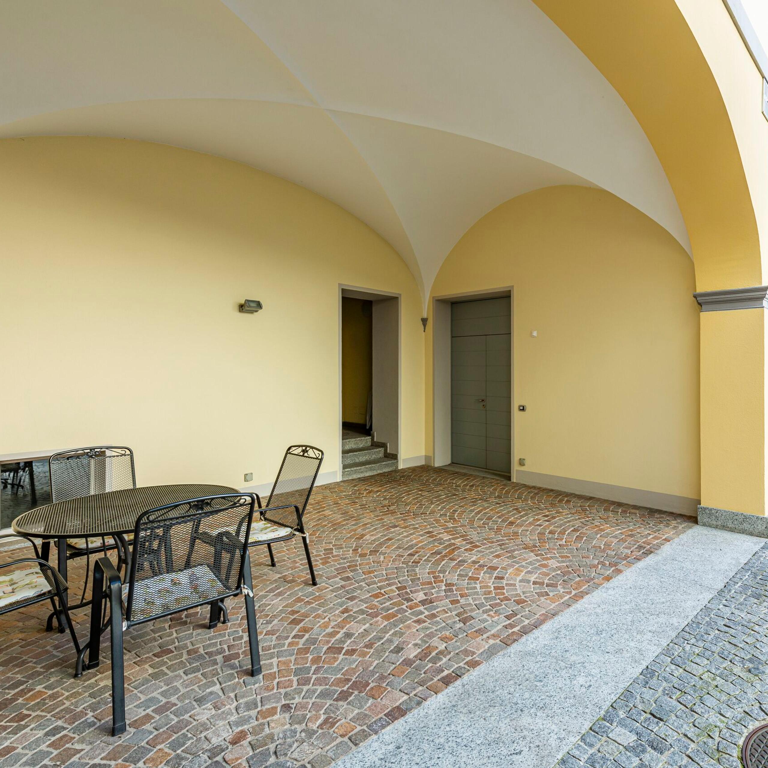 inner backyard, table with chairs, arch, windows, residential building