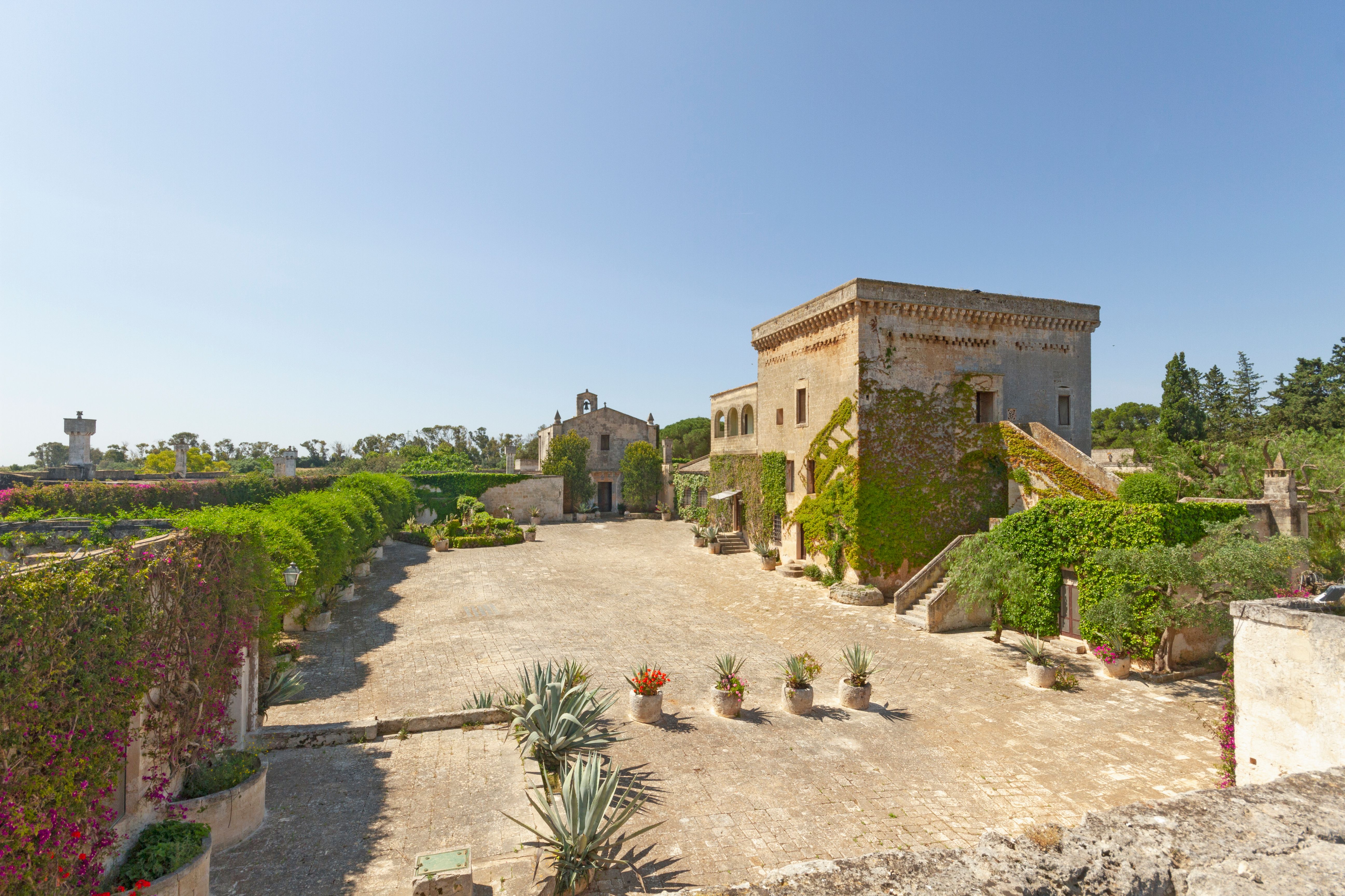 grande patio interno alla masseria, chiesa consacrata e torre saracena, scalini, cielo