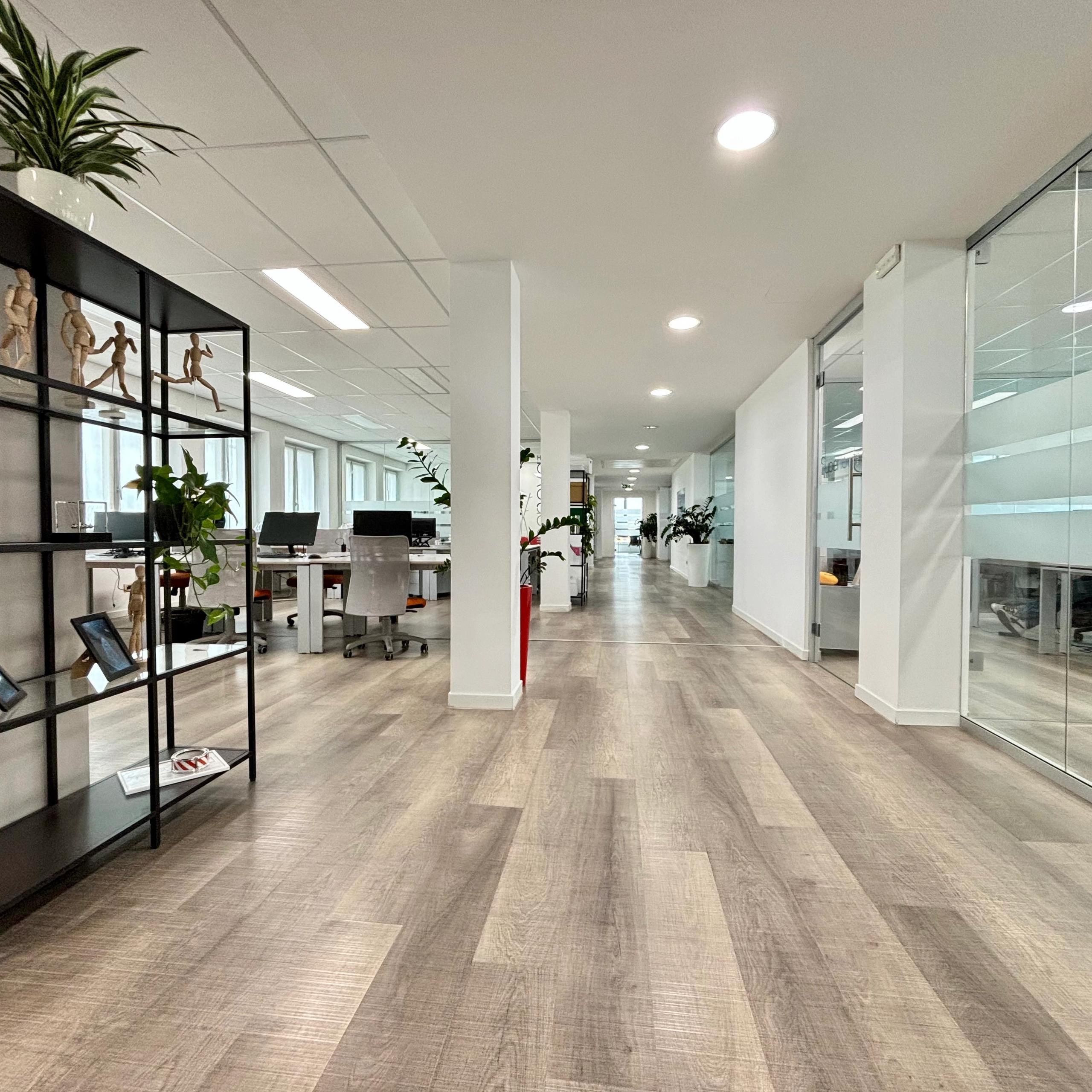 interno ufficio, open sapece, con tavoli e sedie, computer e telefoni, finestre, libreria