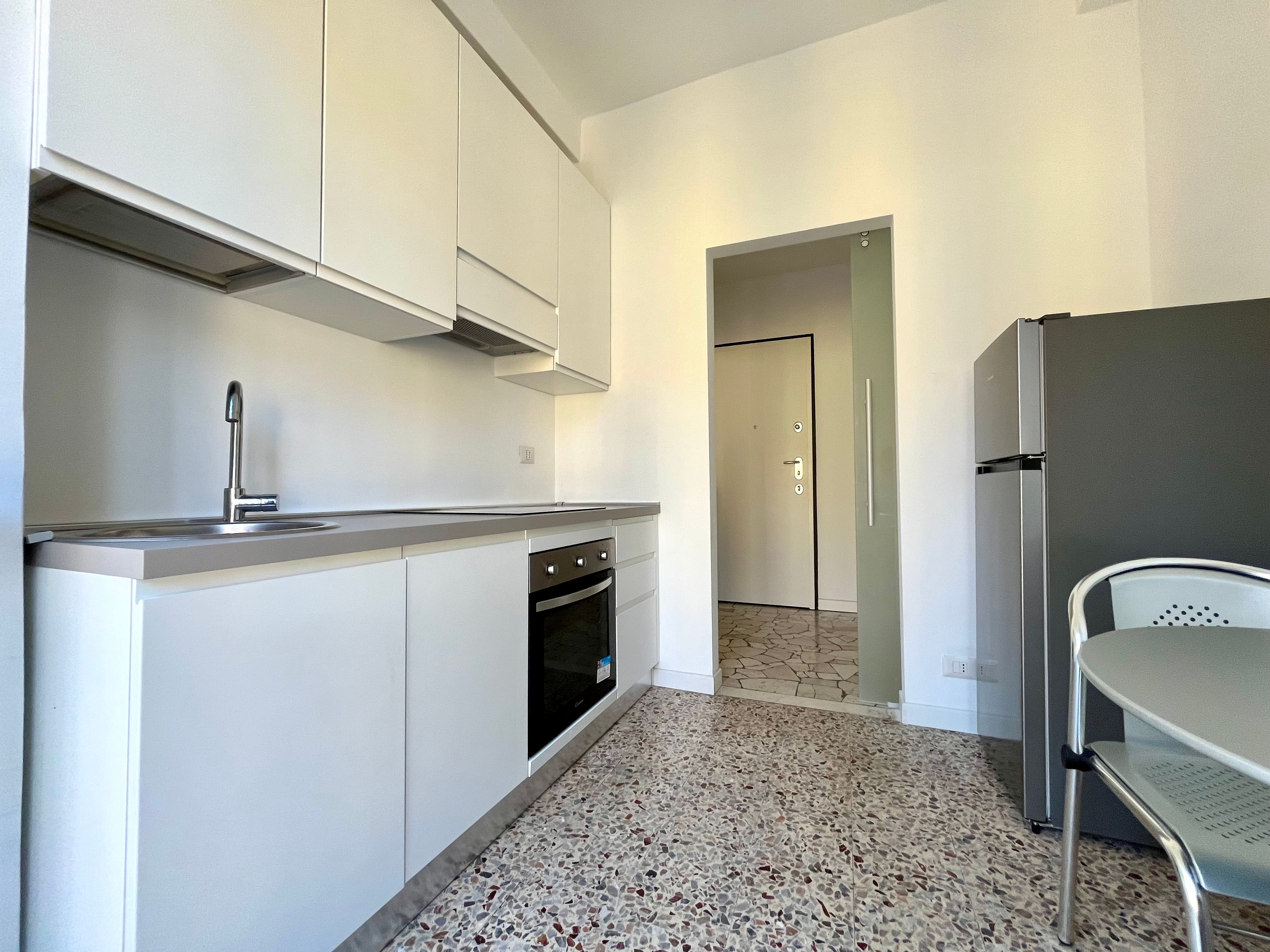 cucina con pavimento in seminato veneziano, forno, lavandino, frigo, tavolo con sedie