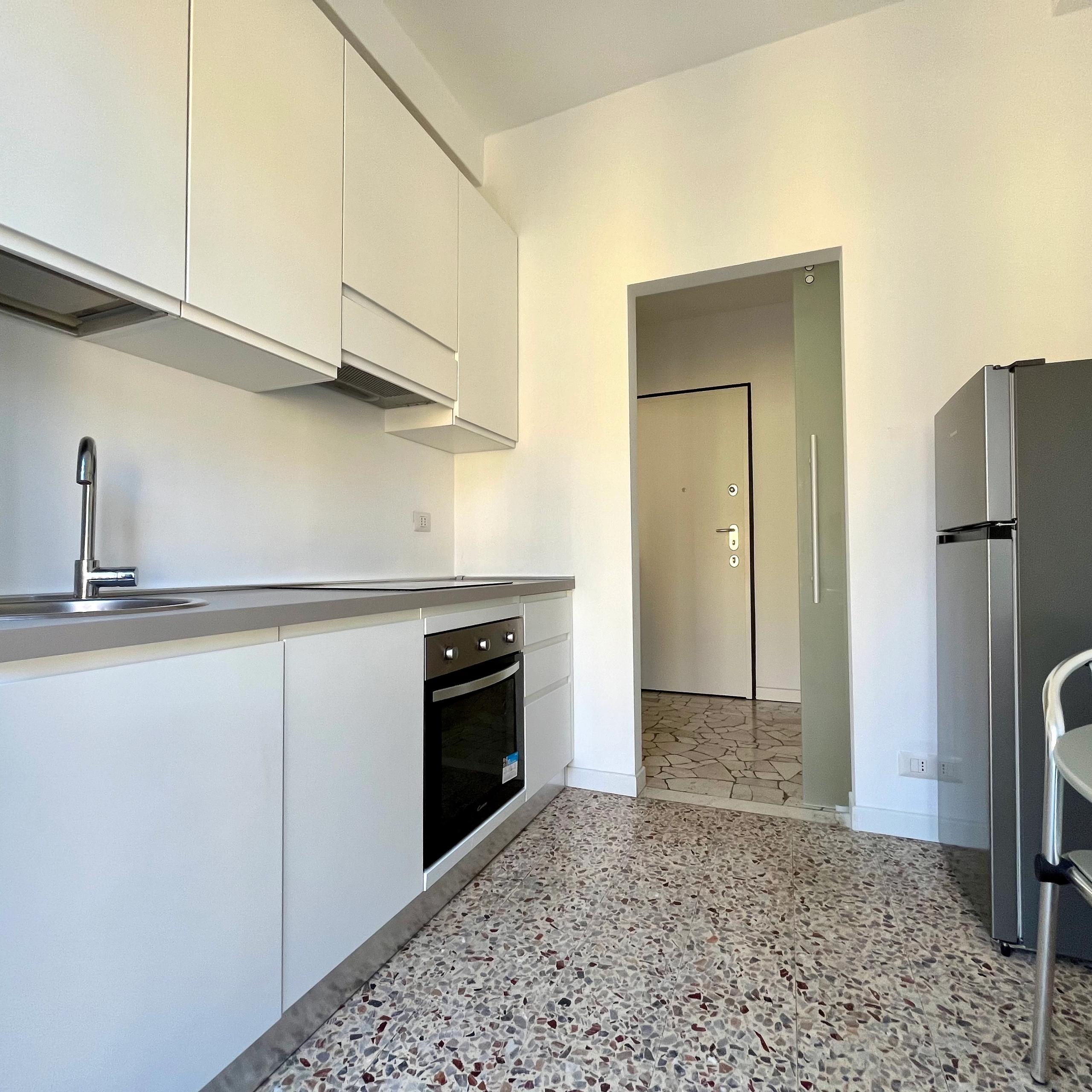 cucina con pavimento in seminato veneziano, forno, lavandino, frigo, tavolo con sedie