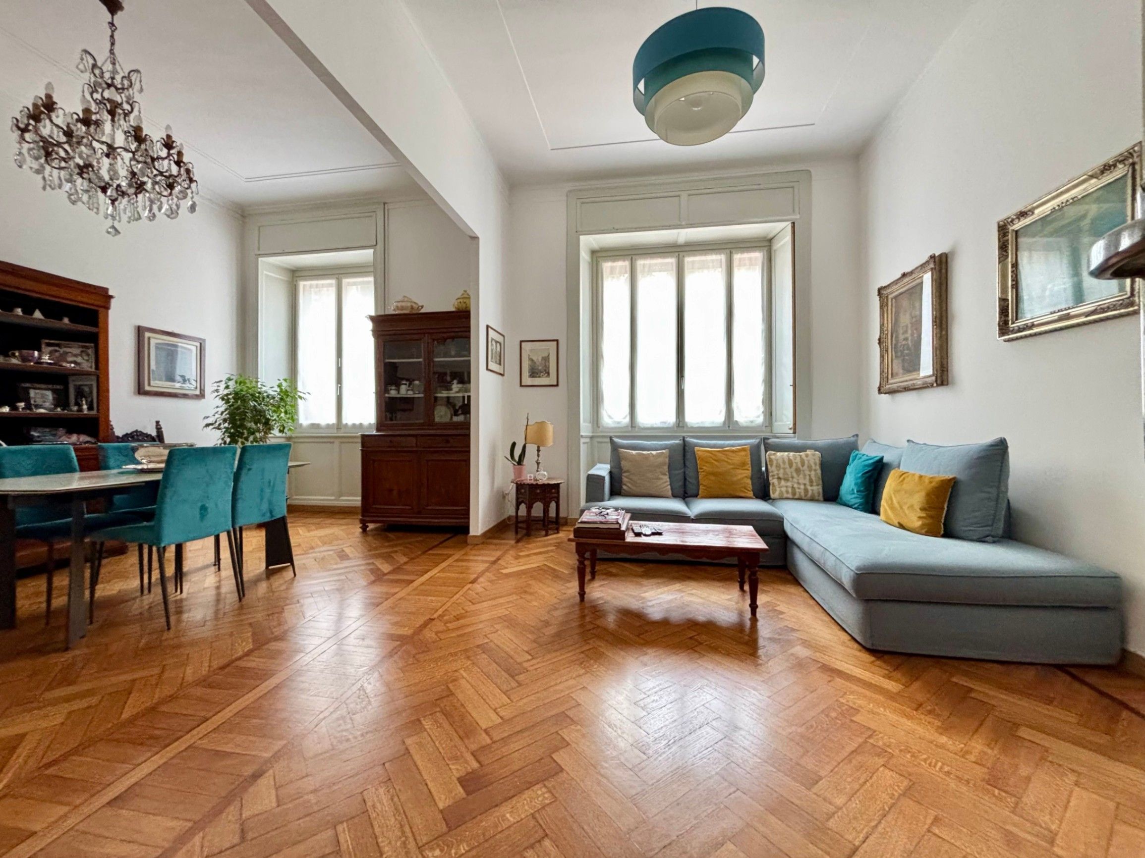 living room with windows, cauch, coffe table, dining room with table and chairs, chandelier