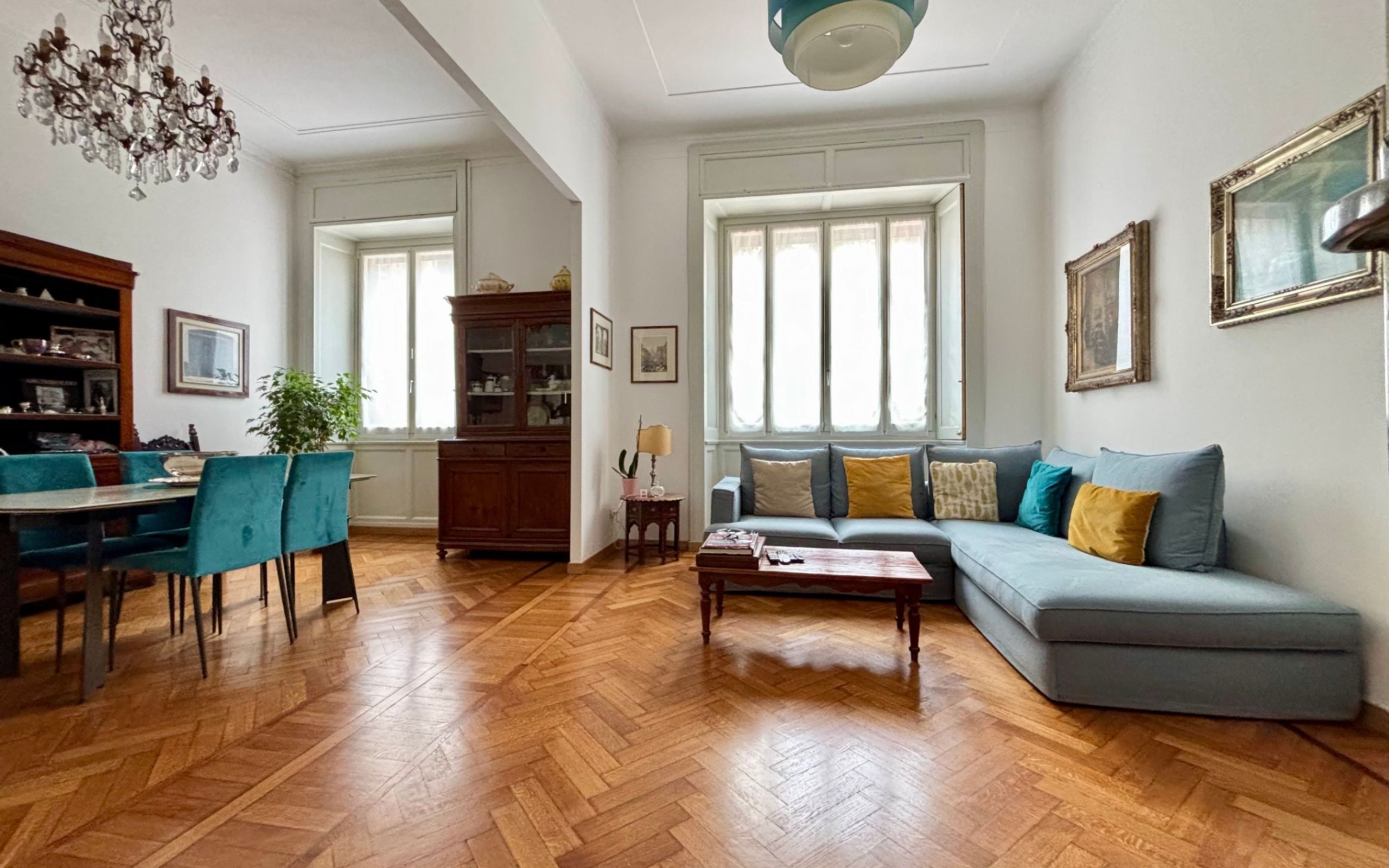 living room with windows, cauch, coffe table, dining room with table and chairs, chandelier