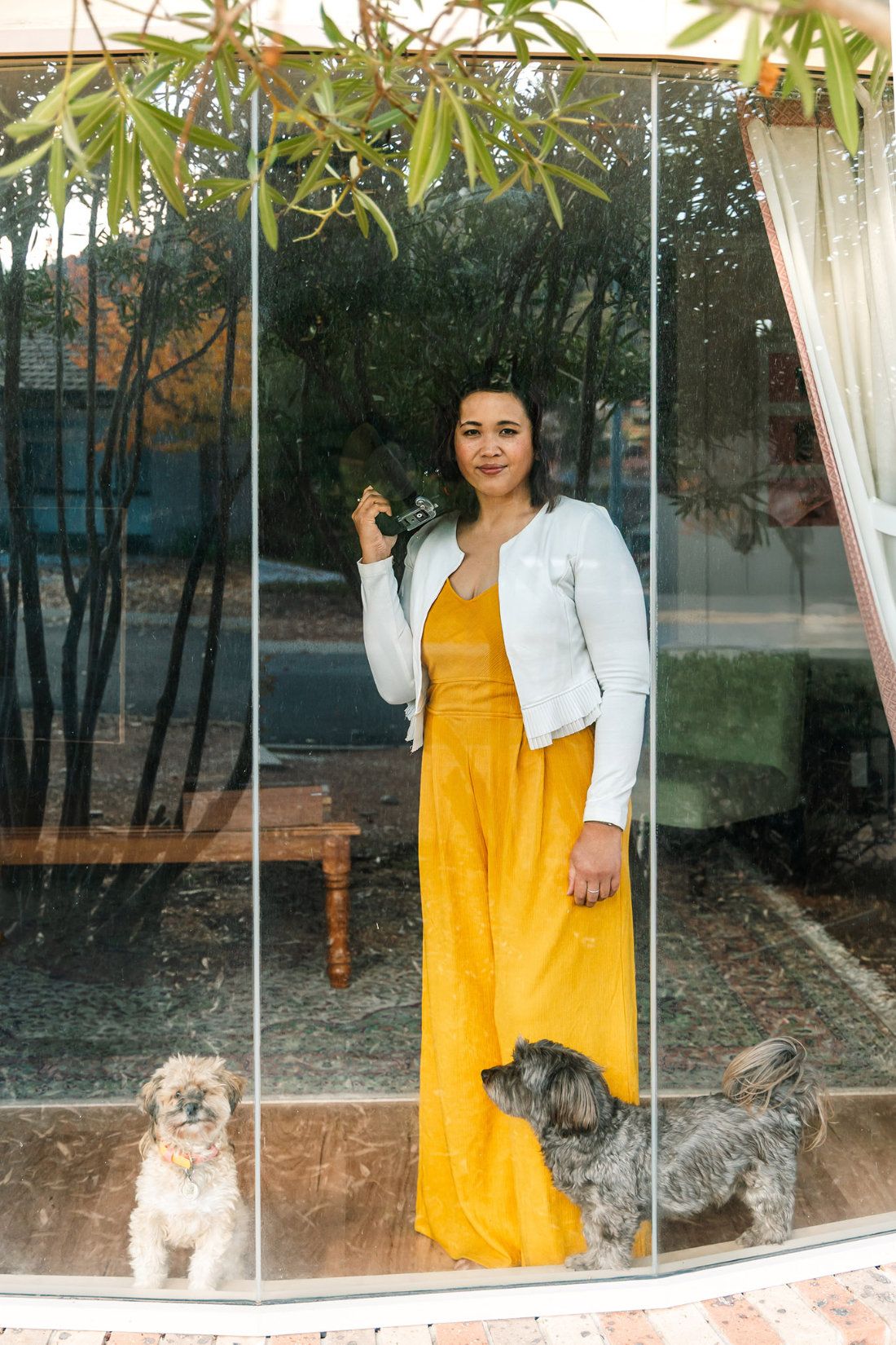 Pet photographer Ina J holding her Sony camera in the studio in front of framed dog portraits