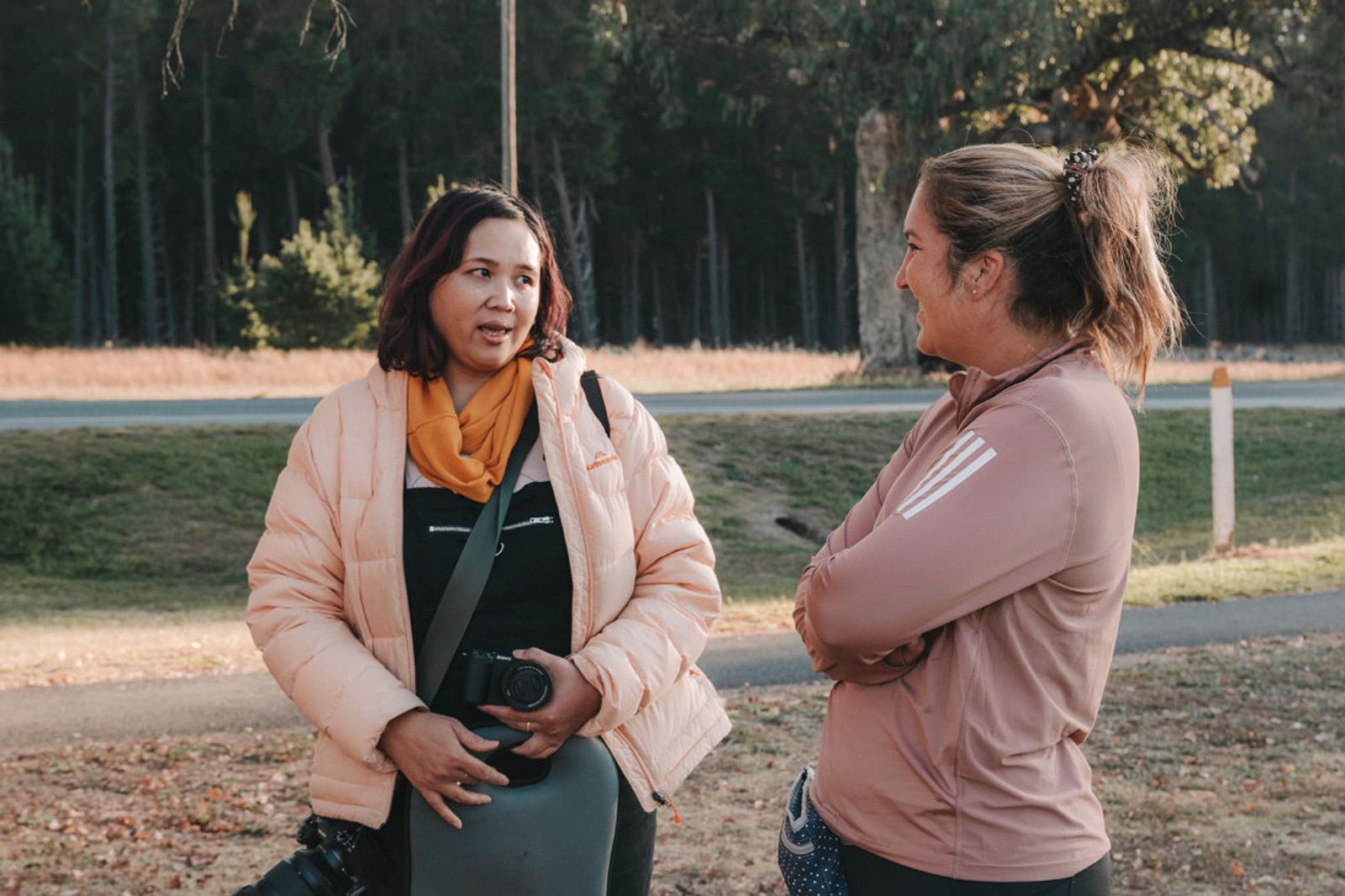 Pet photographer Ina J in a peach jacket talking with a client outdoors at a park