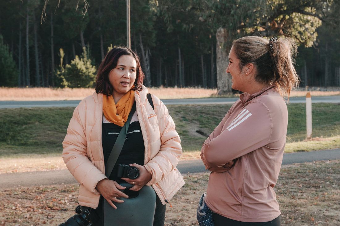Pet photographer Ina J in a peach jacket talking with a client outdoors at a park