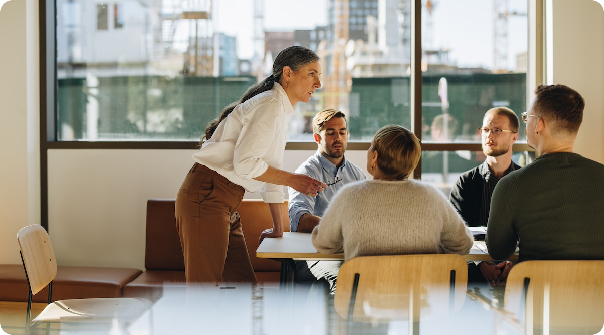 Experienced business woman standing over conference table addressing team