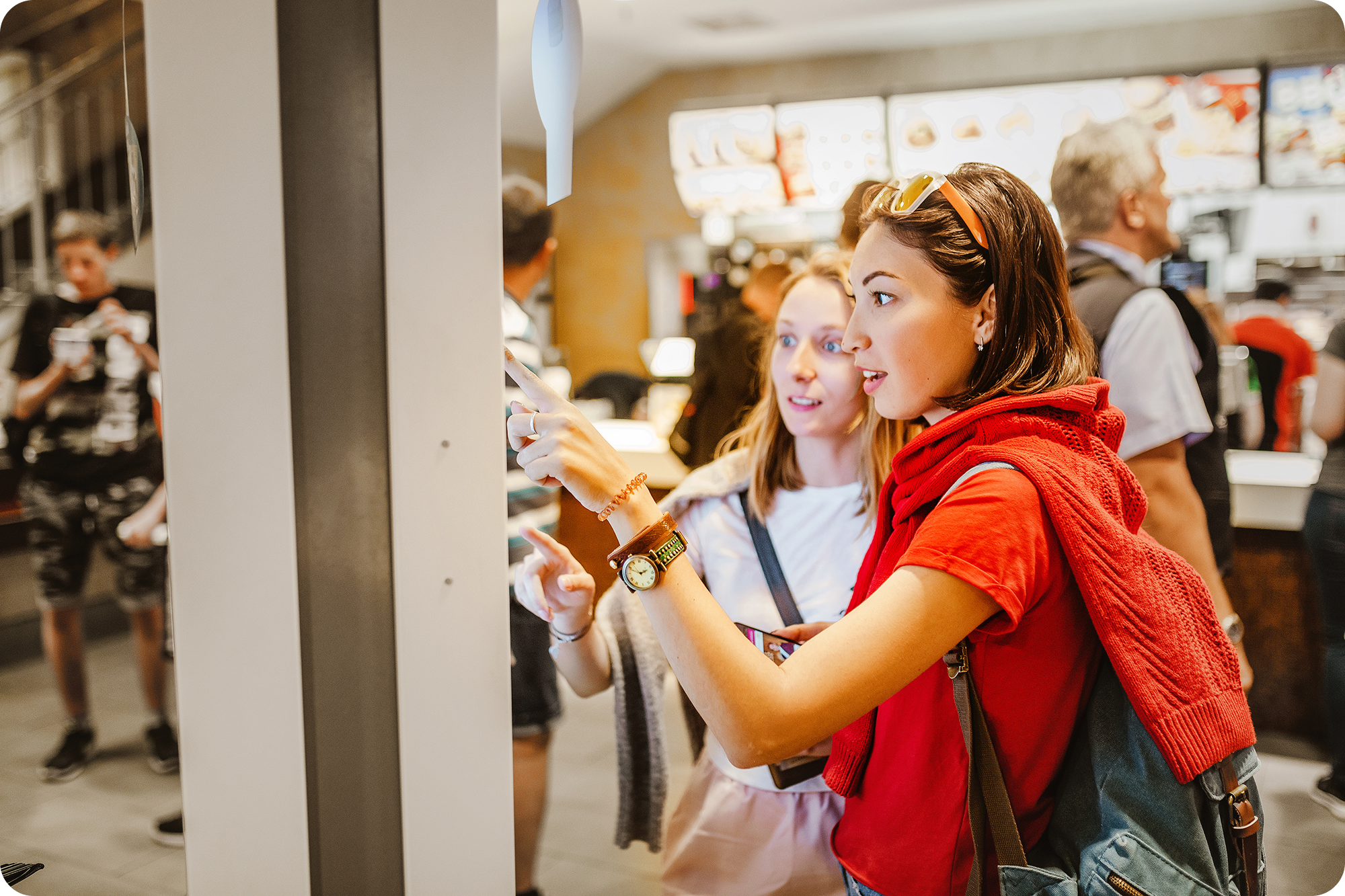 Two young girls ordering from a digital fast food kiosk