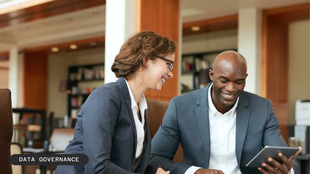 Two smiling business people look at a tablet together.