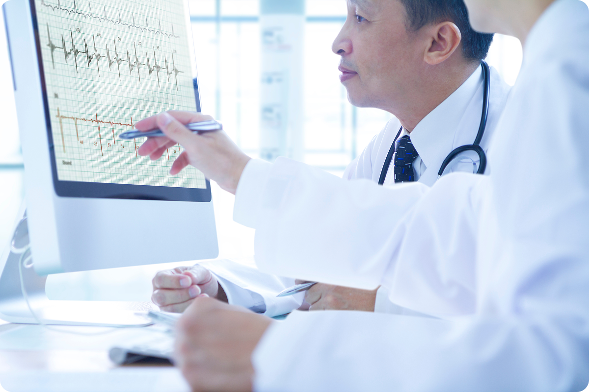 Two doctors looking at a patients health data on a desktop computer