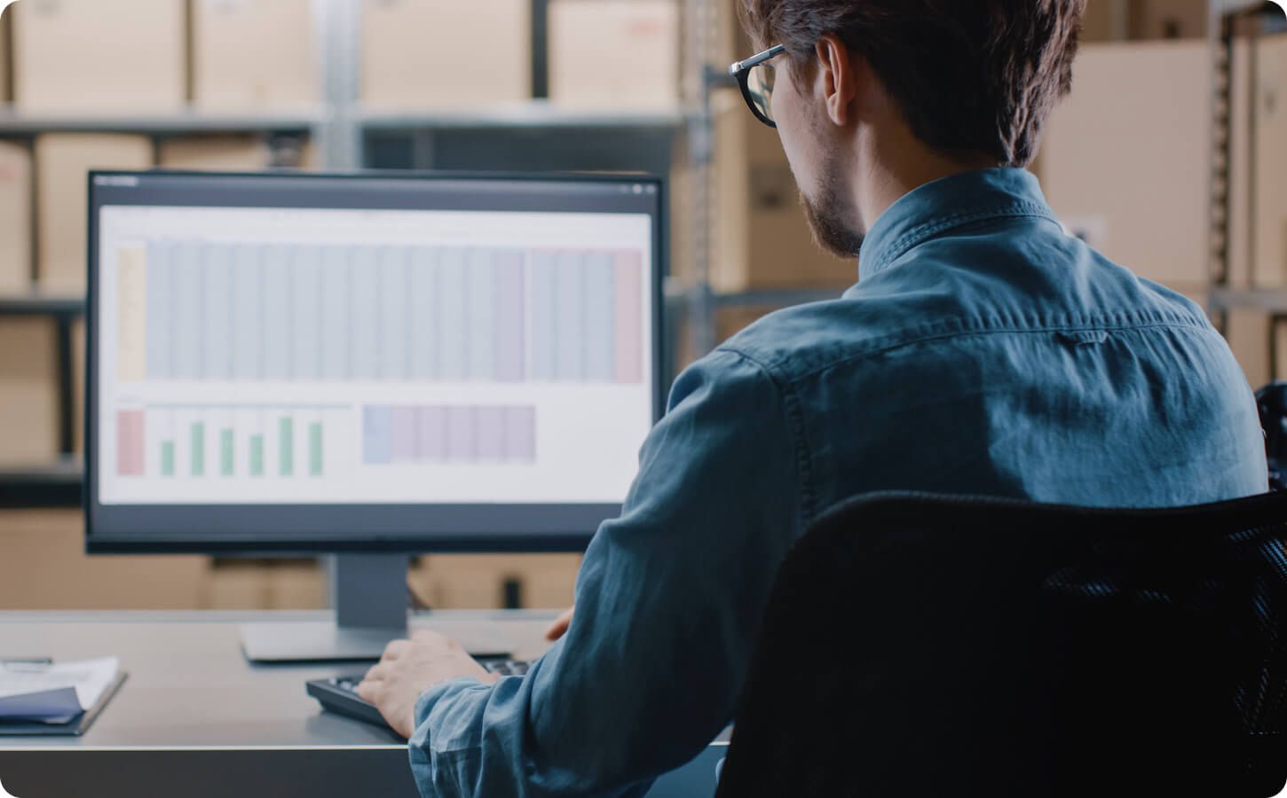 An over the shoulder view of professional working on spreadsheet at desk