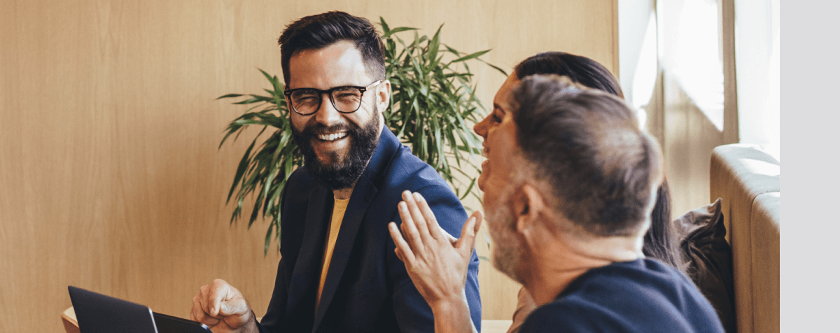 Group of professionals smiling and laughing around modern office setting