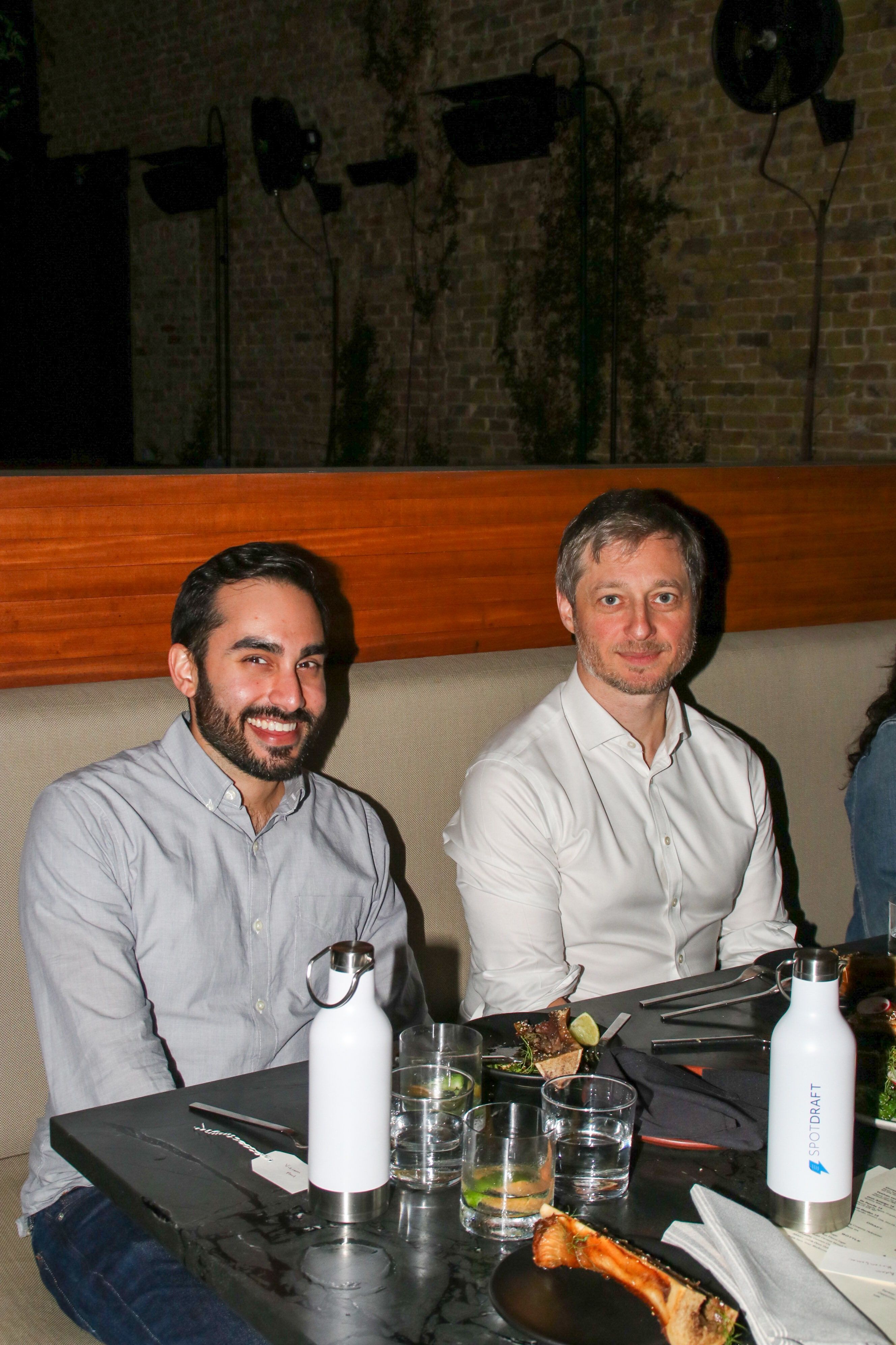 Two men sitting at a restaurant table smiling