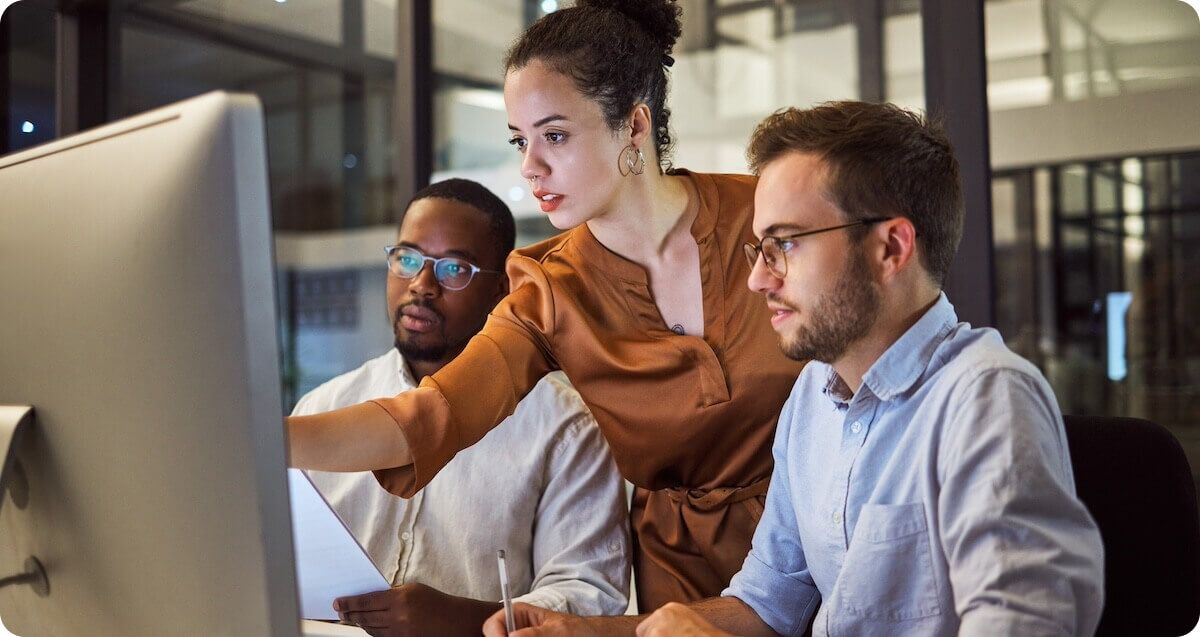 Three professionals sitting around computer working