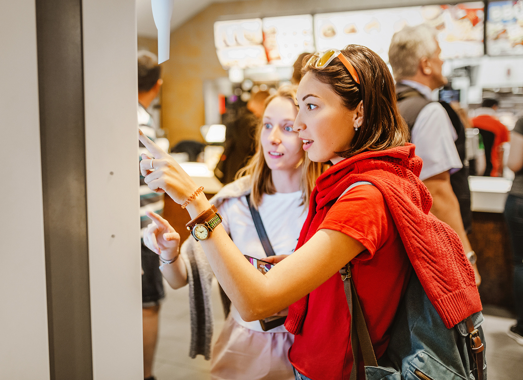 Two young women ordering from a digital kiosk at a fast food restaurant