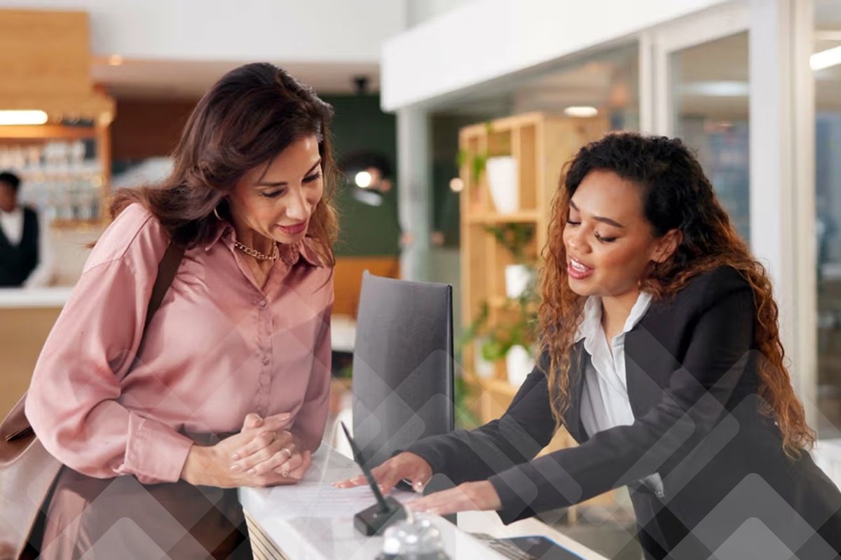 A receptionist and guest reviewing documents at a front desk.