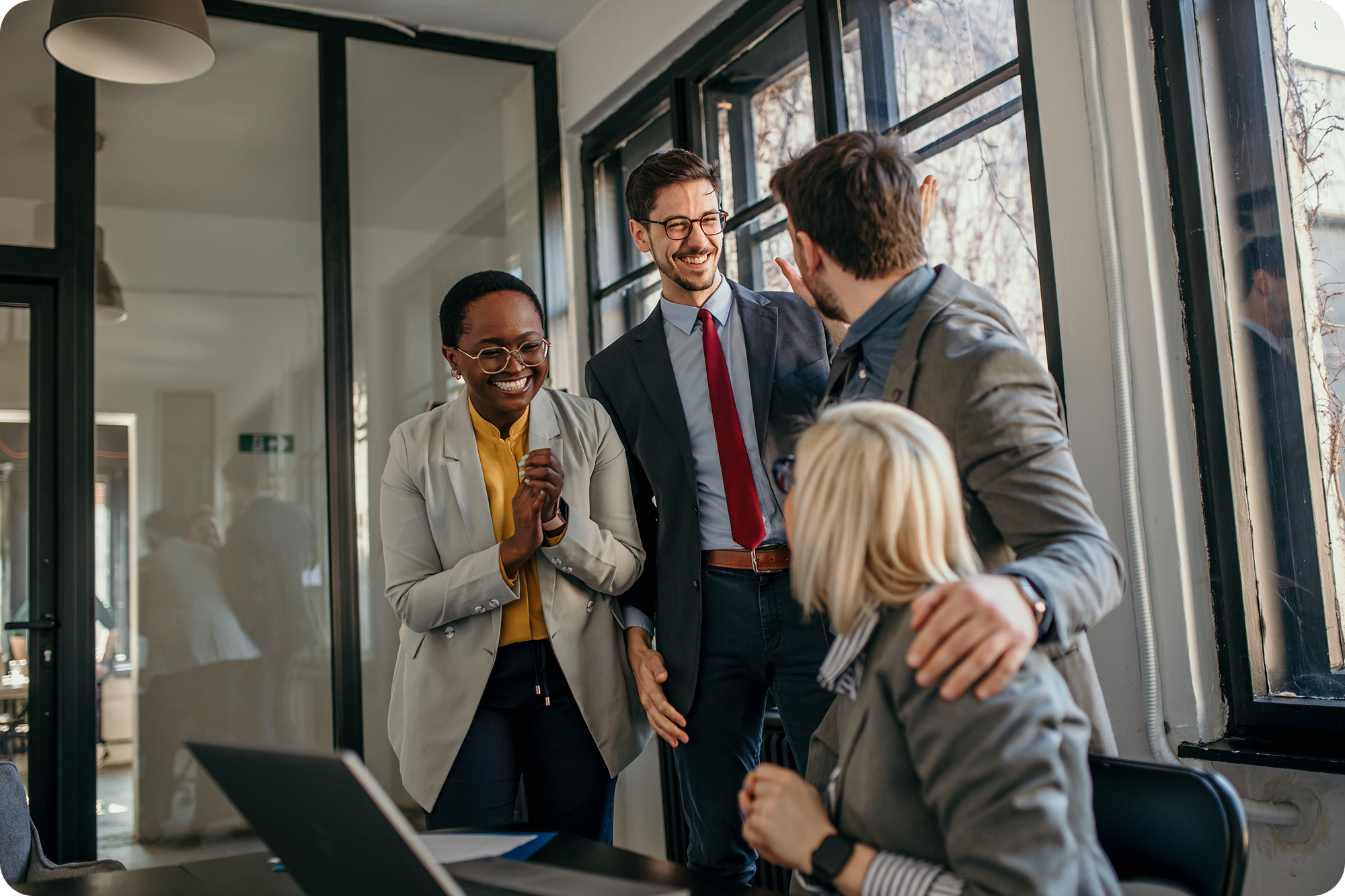Four professionals smiling and laughing in a downtown office