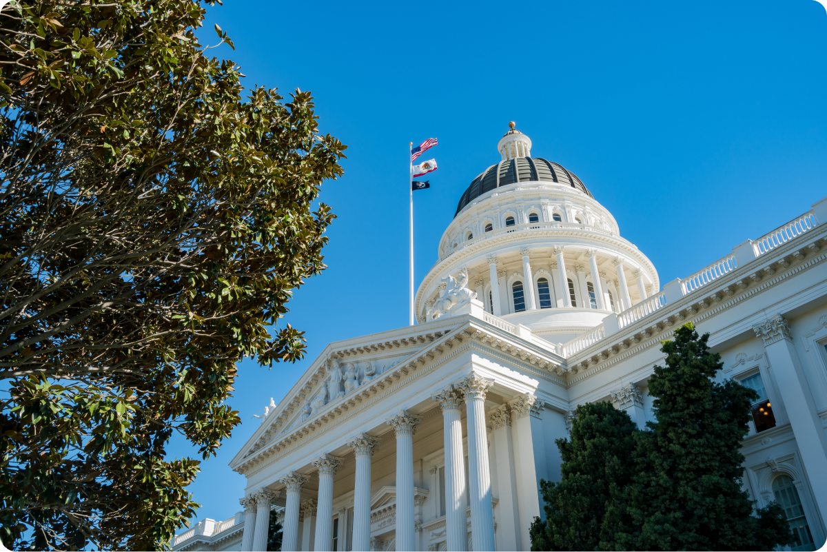California capitol building in Sacramento, CA with an American flag and a California state flag