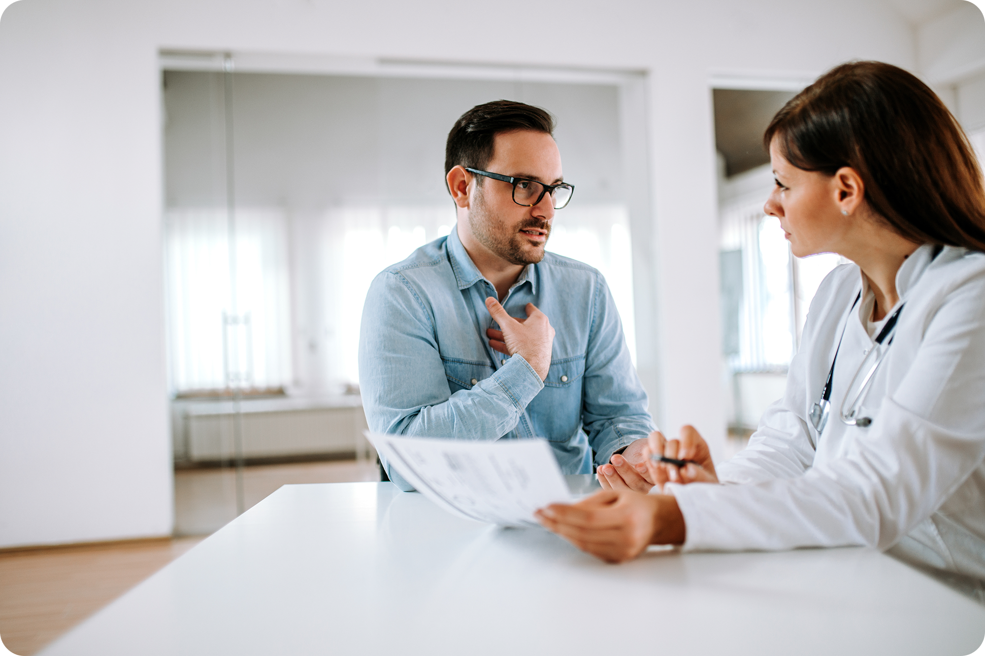 Man with glasses talking to a medical professional