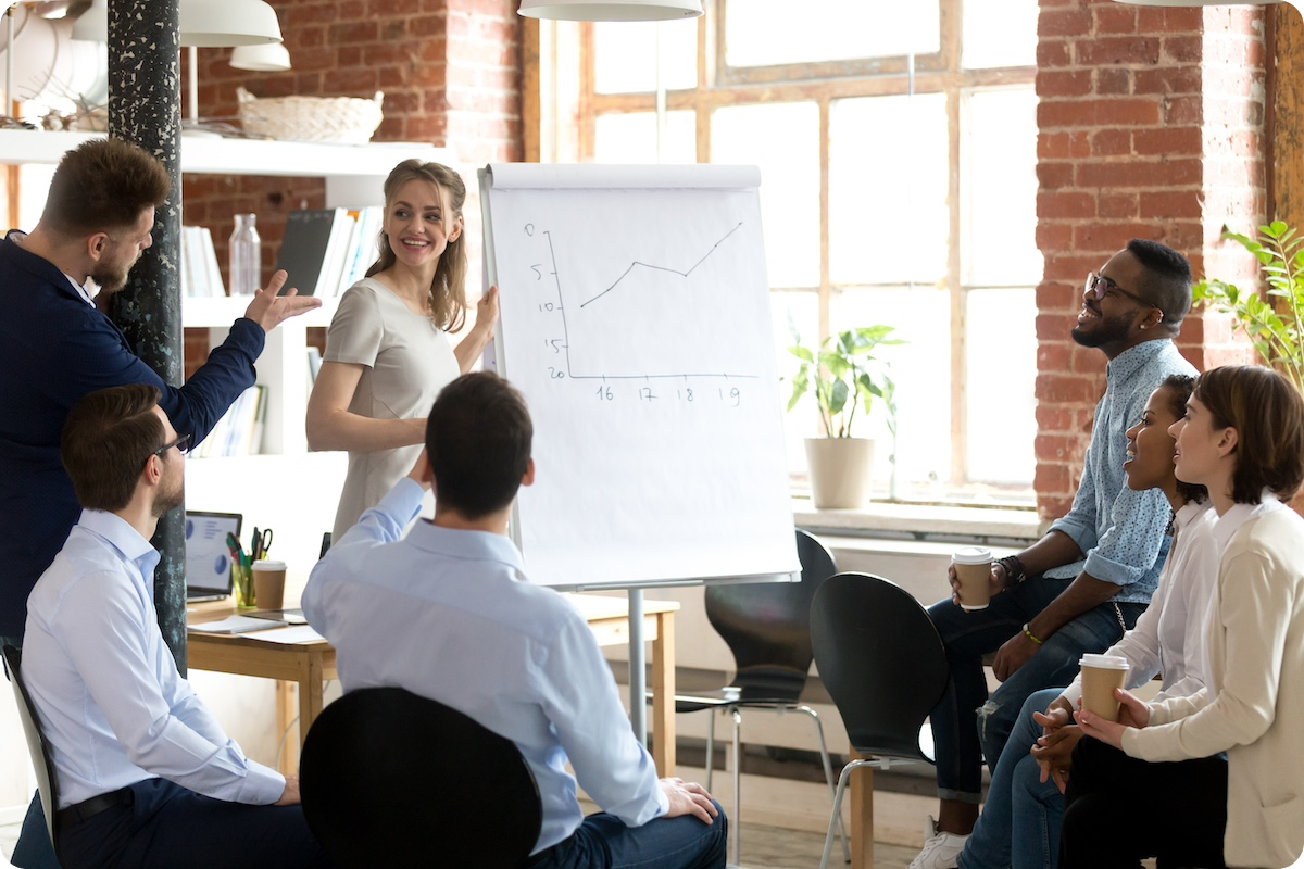 Group of business professionals huddled around large notepad with hand-drawn line graph