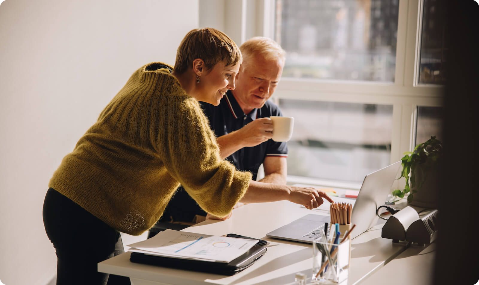 Man and woman reviewing computer on desk and smiling as they evaluate a consent management plaform