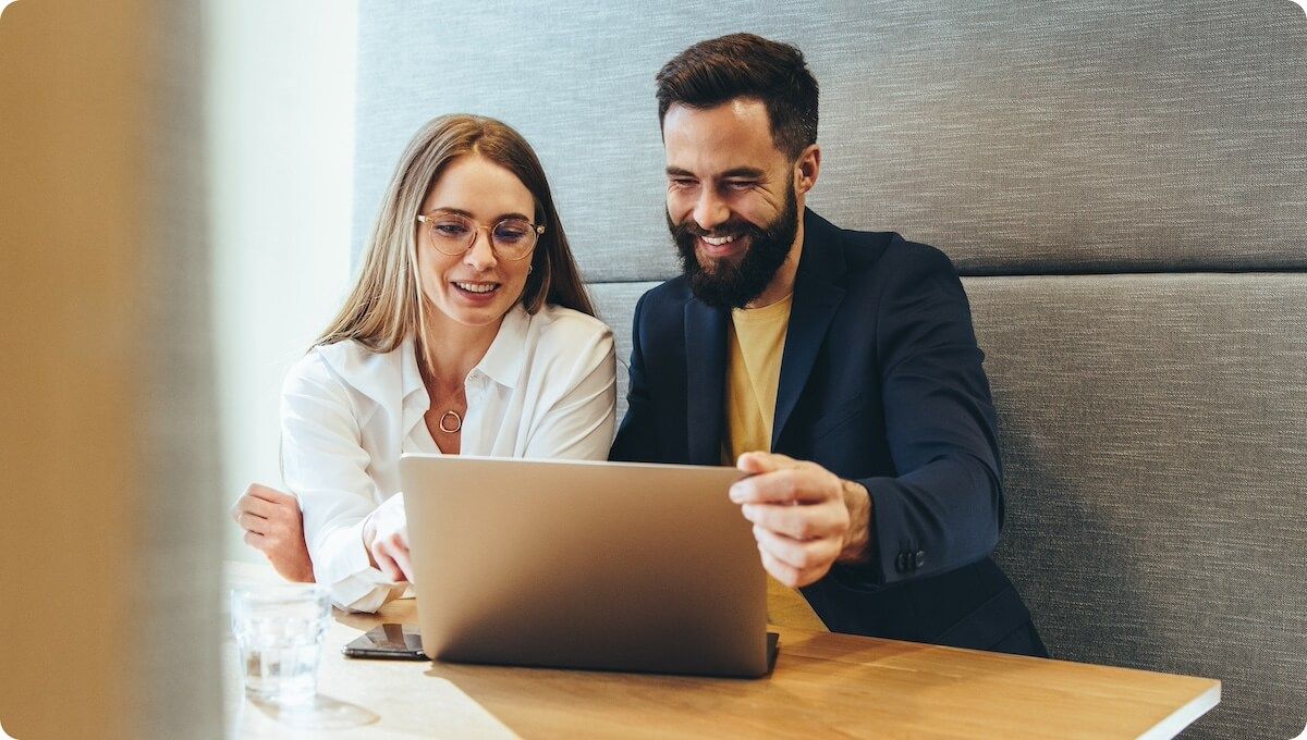 Two professionals sharing laptop in modern office