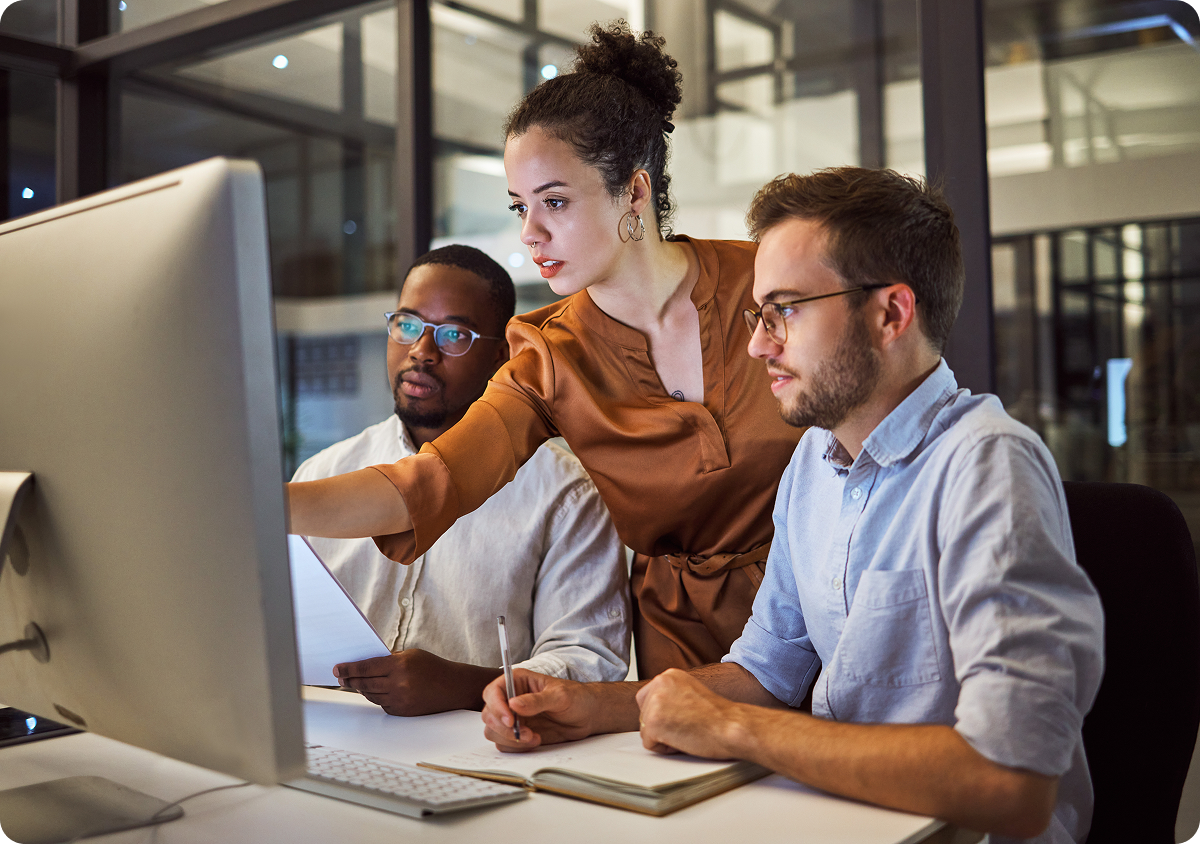 Three young professional looking at a desktop computer while they work on securing personally identifiable information
