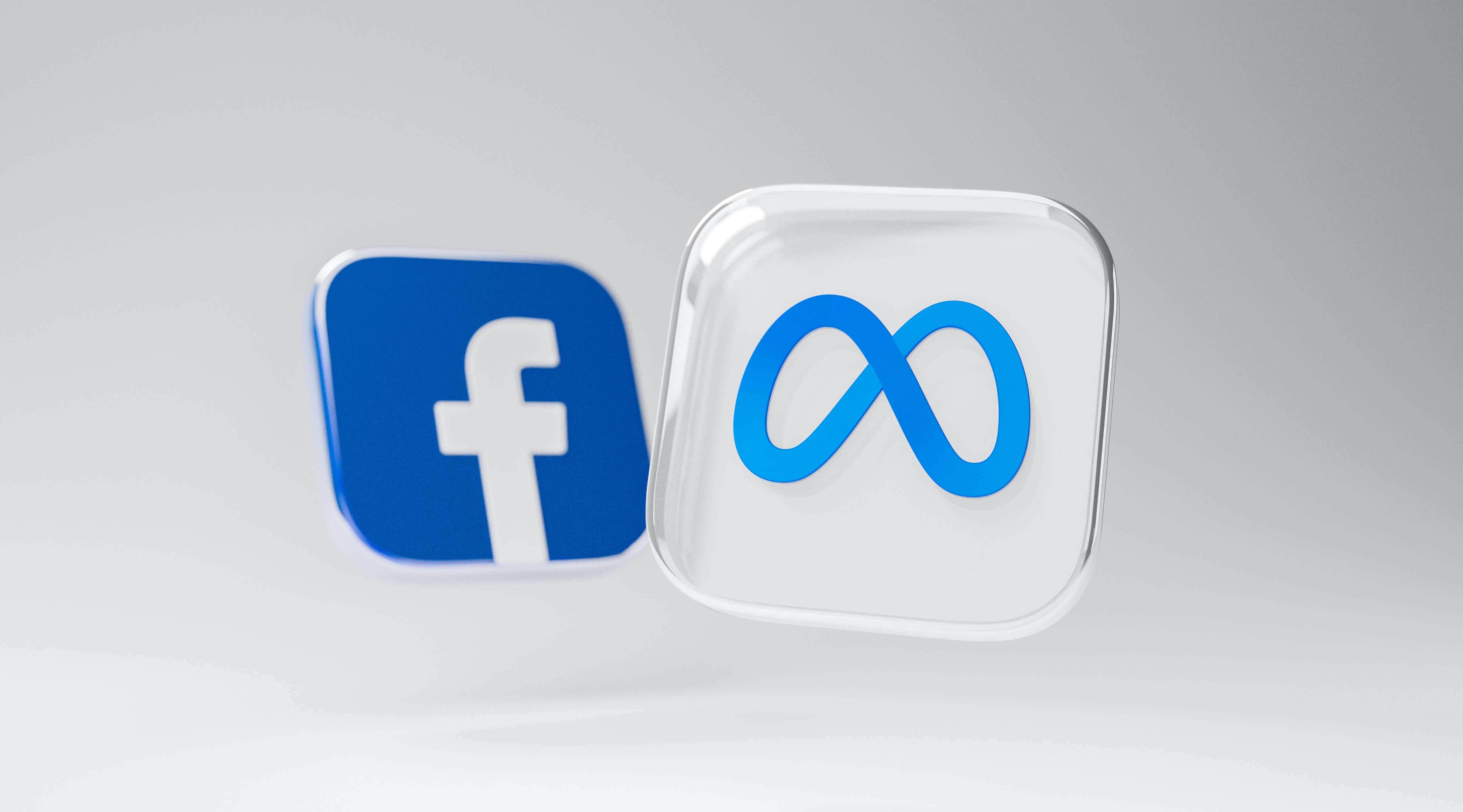 Two three dimensional logos of Meta and Facebook floating in white space