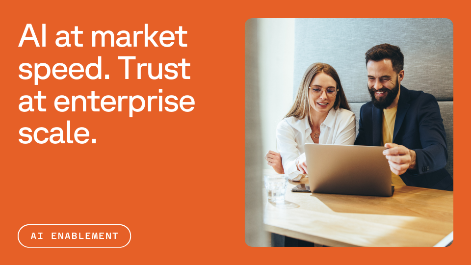 Two people sitting at a table, smiling and looking at a laptop together, with a text overlay that reads "AI at market speed. Trust at enterprise scale." The image is on an orange background with a button labeled "AI Enablement."