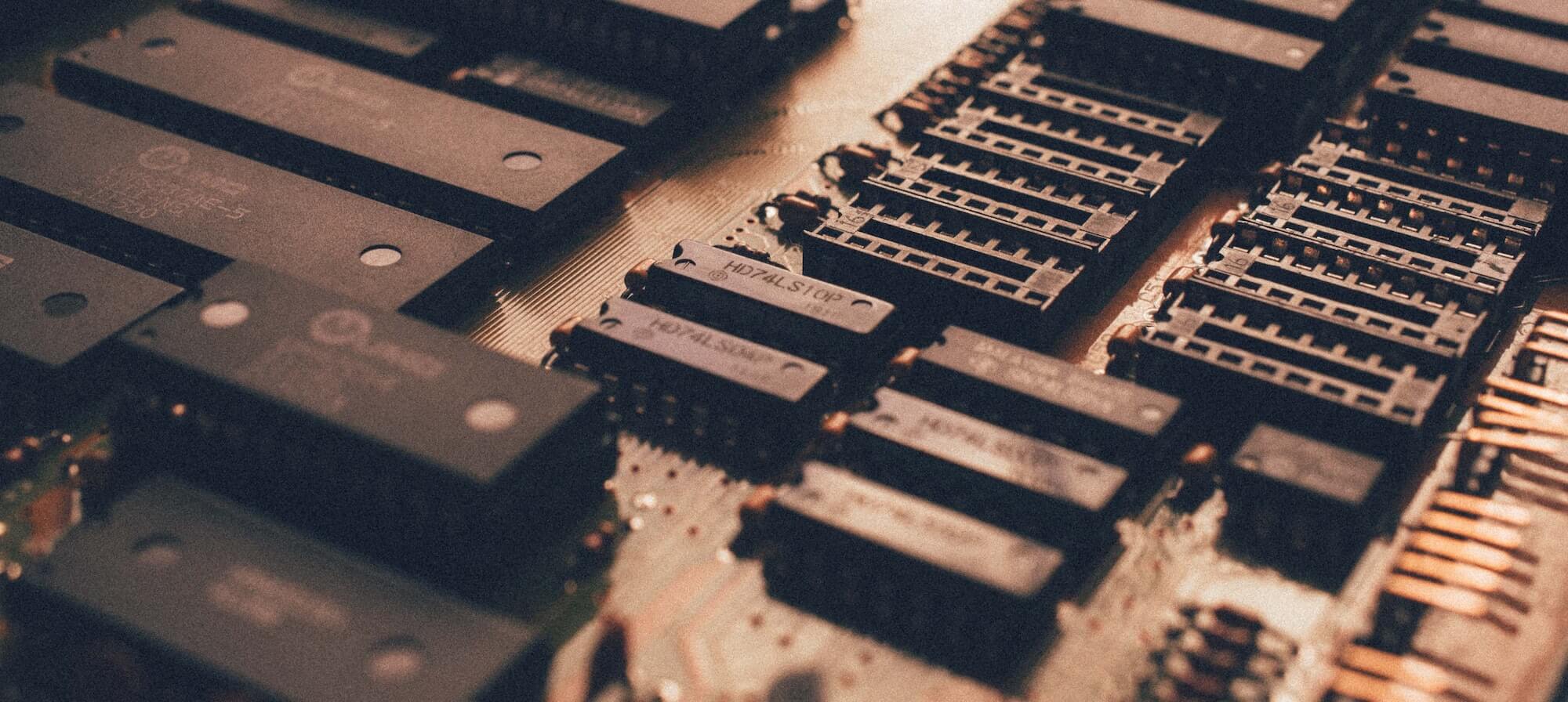 A close-up view of numerous integrated circuit chips and components mounted on a circuit board, featuring labels and metallic connectors.