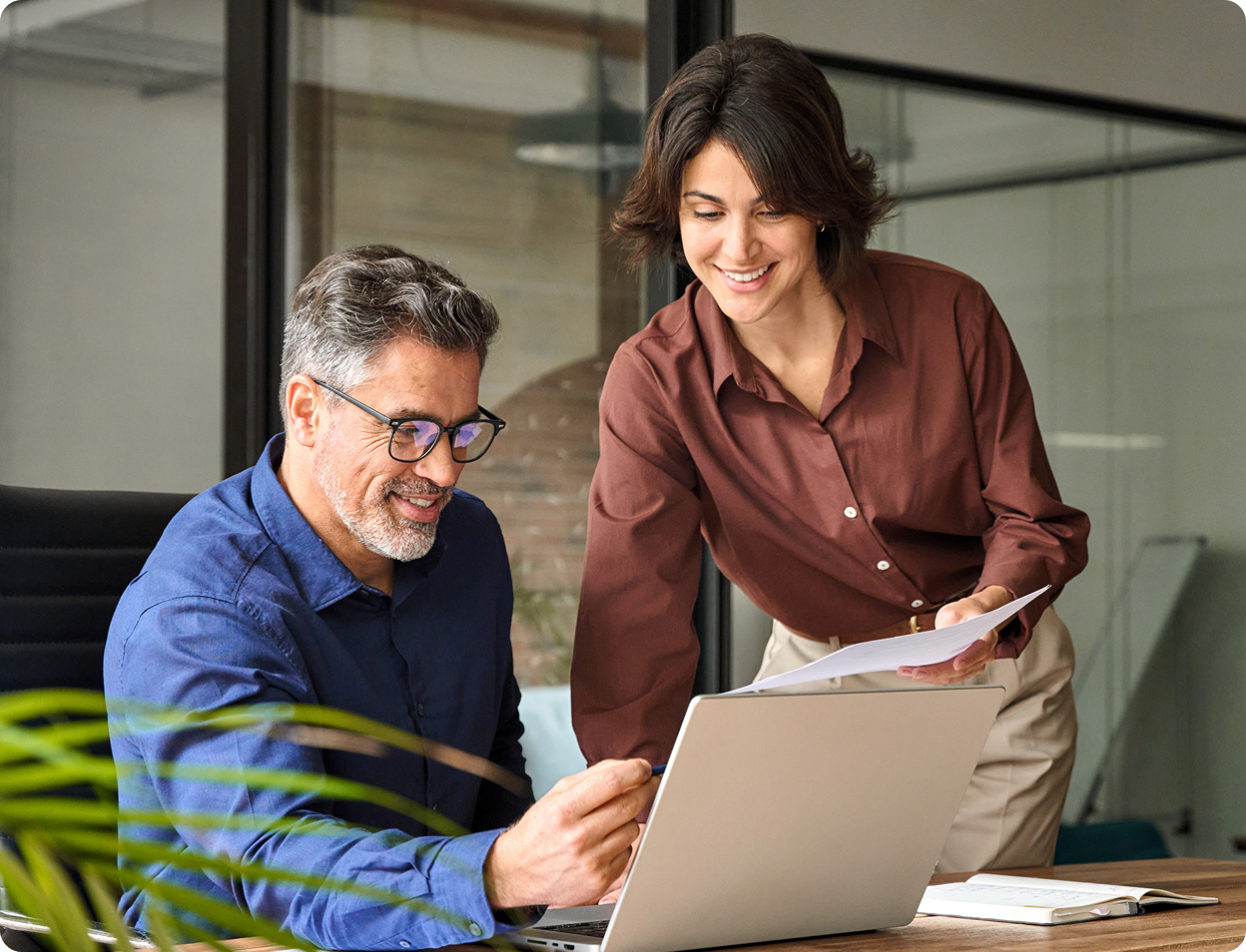 Two professionals looking at a laptop and smiling